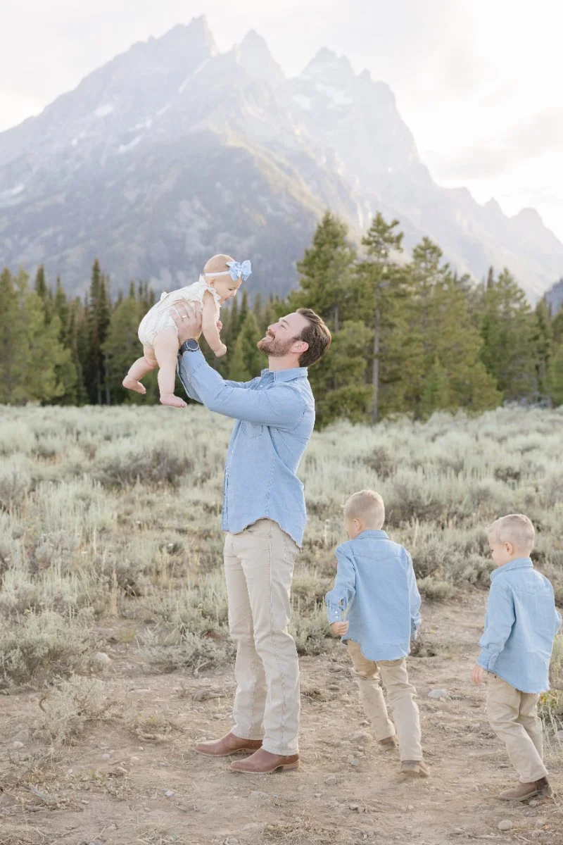  Dad lifting his baby during a Grand Teton National Park family photo session while traveling with babies in Jackson Hole. 
