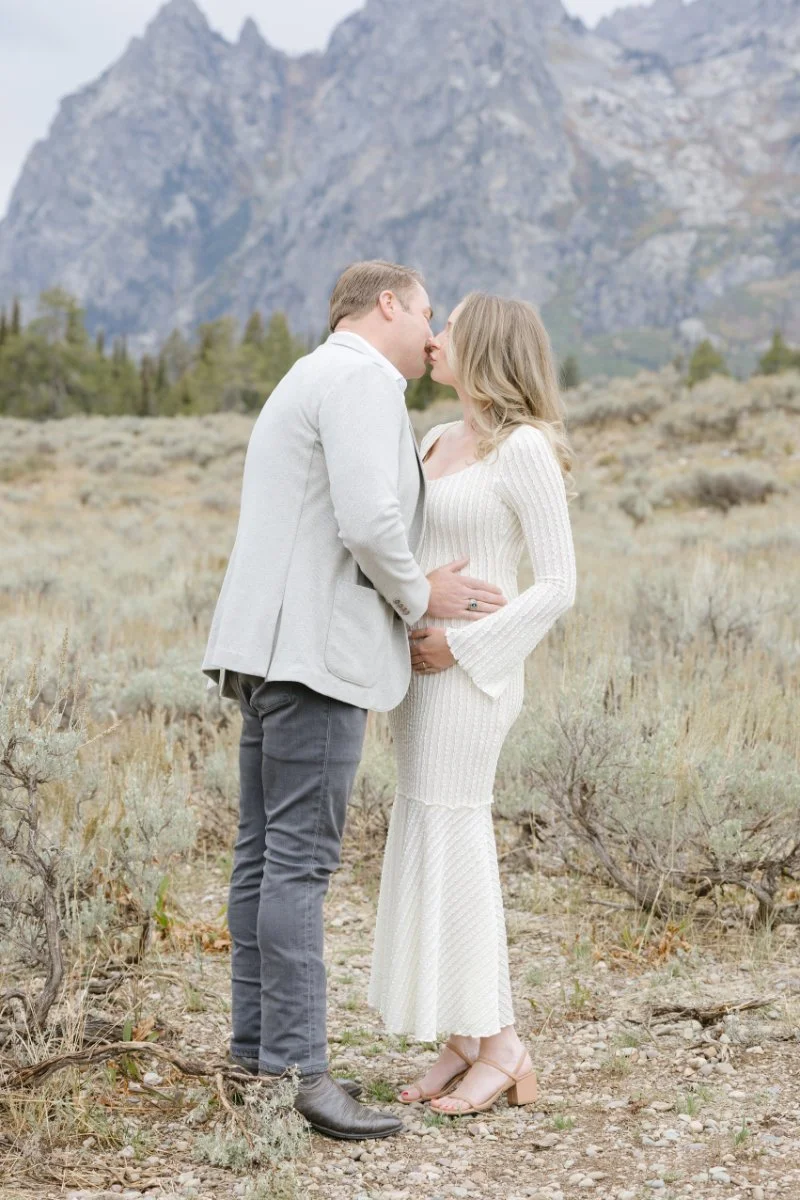   Pregnancy photo announcement session in Jackson Hole featuring an expecting couple beneath the Tetons    