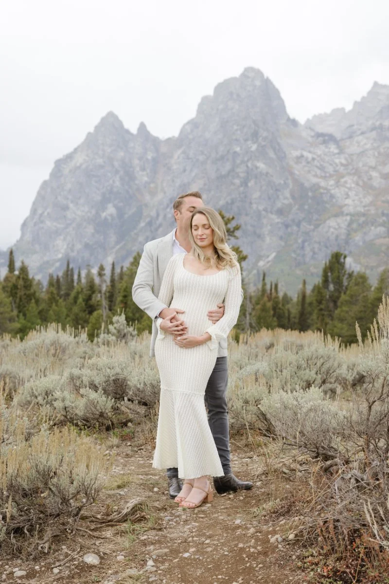   Pregnancy photo announcement session in Jackson Hole with expecting parents in front of the Tetons    