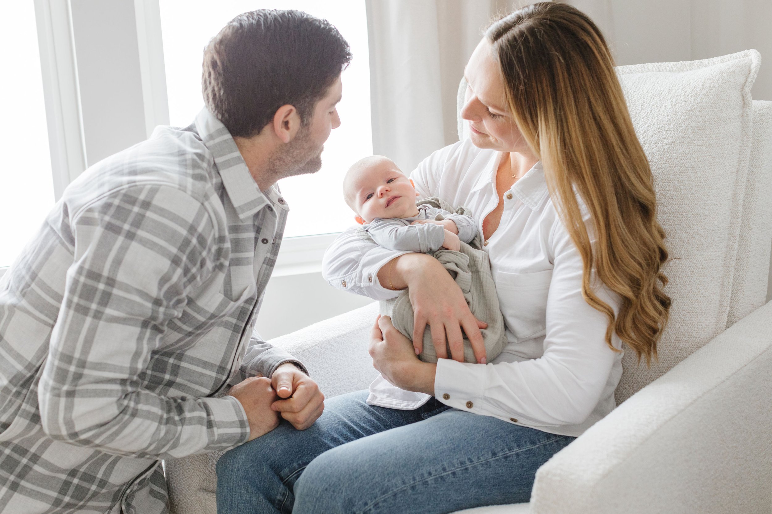 Newborn photographer in Jackson Hole captures mom and dad in nursery as they rock baby.