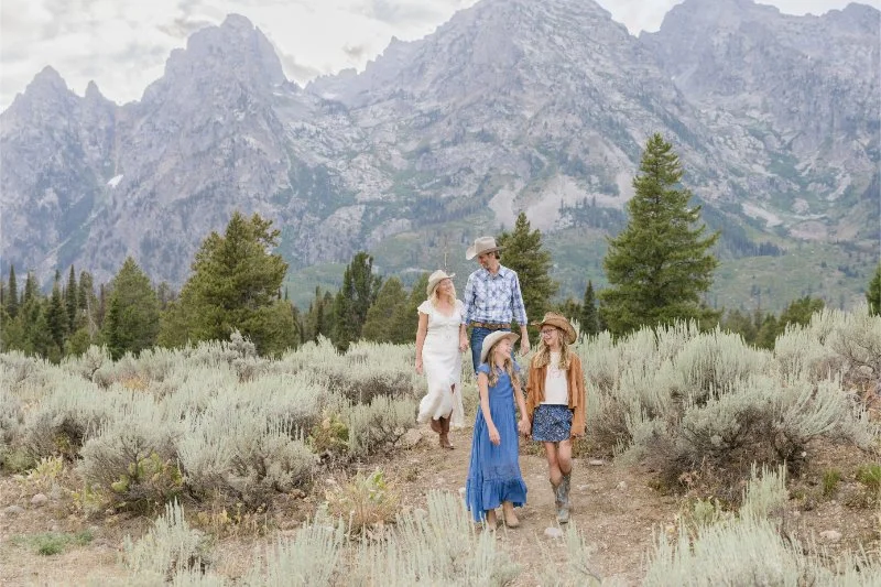 Family walking together on a trail during a Mother’s Day photoshoot in Jackson Hole with the Tetons and sagebrush landscape in the background