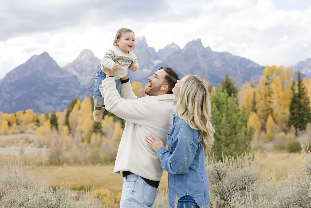 Family standing together in a fall field in Grand Teton National Park with warm golden tones and mountain backdrop