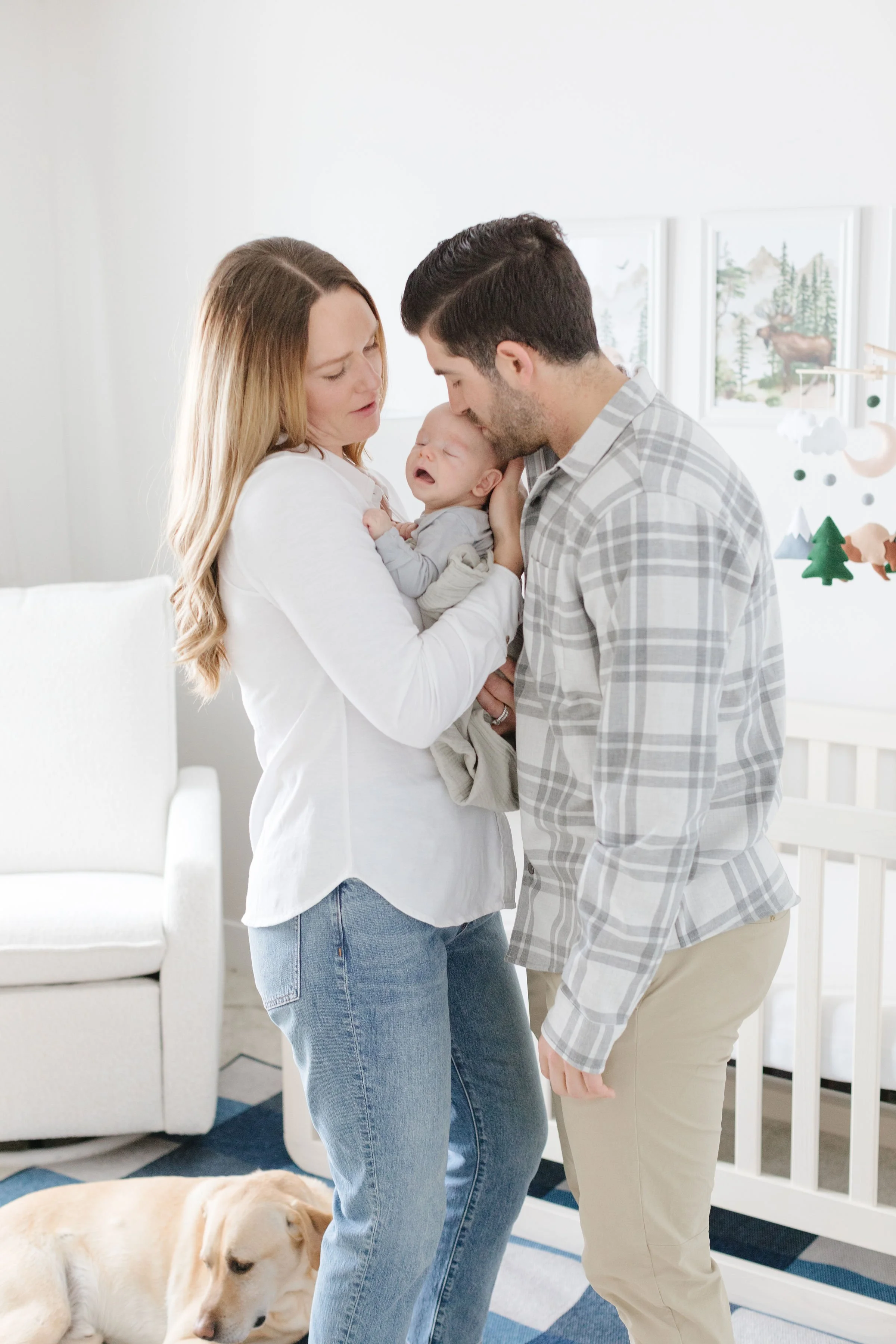 New parents pose in Jackson Hole nursery for family newborn pictures at home.