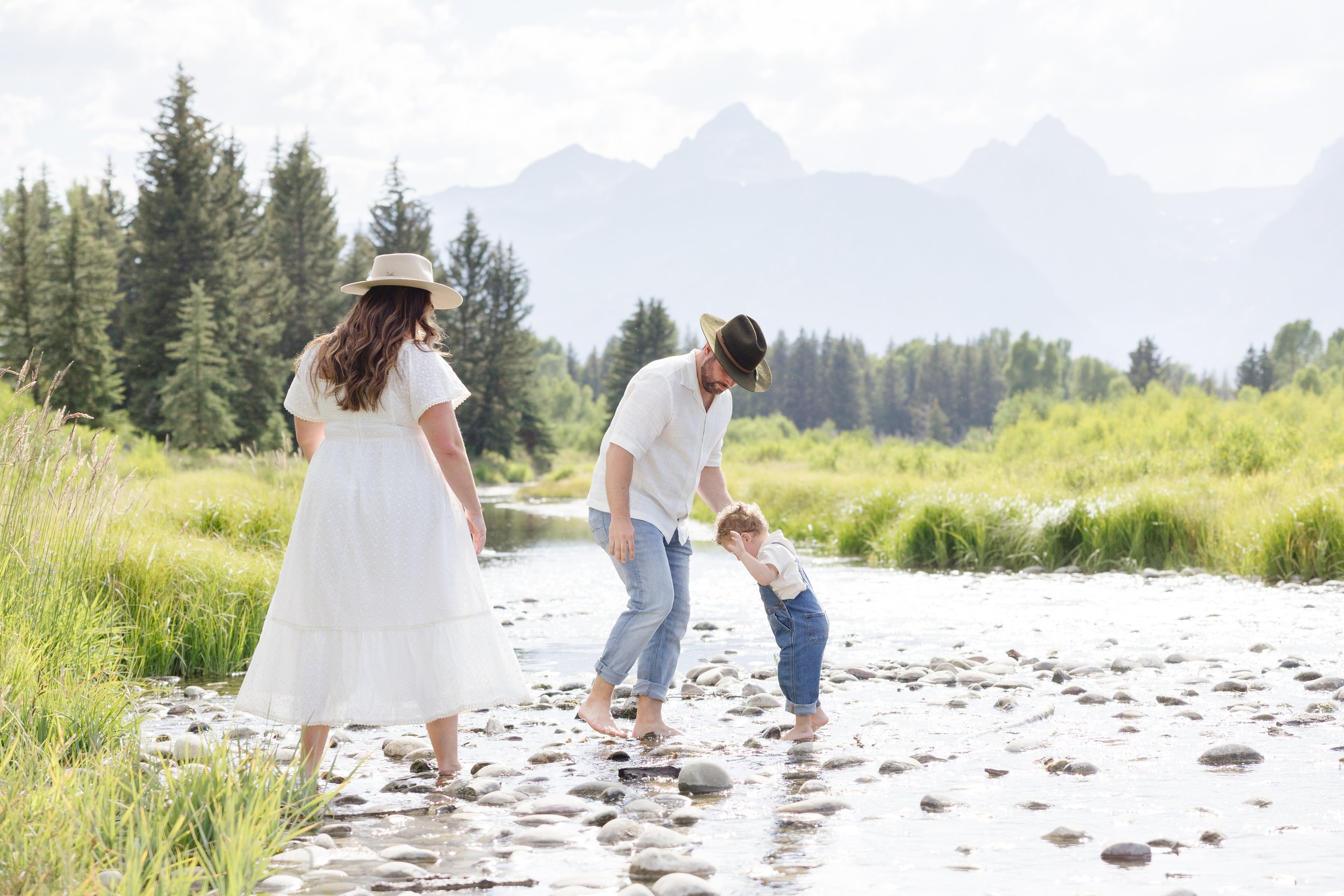 Family walking barefoot in a creek in Jackson Hole with mountain views, enjoying one of the best hikes in Jackson Hole