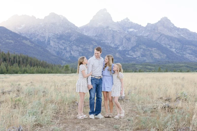 Father with three daughters at the Grand Tetons taking a family picutre.