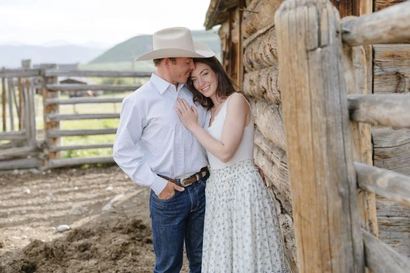 Couple embracing beside a rustic cabin in Jackson Hole after a romantic proposal at one of the most charming places to propose in the Tetons