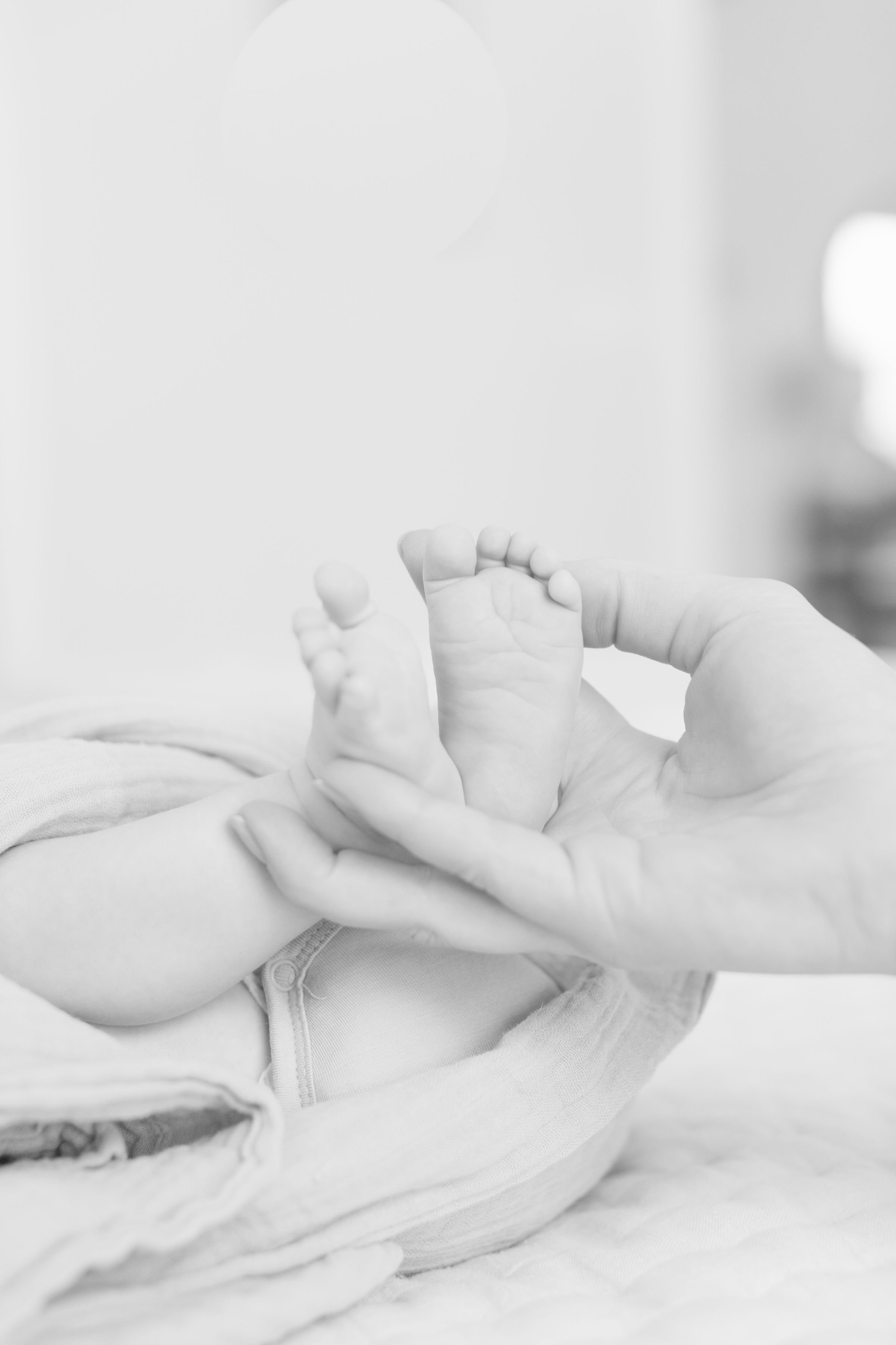 black and white photo of mom holding her baby's feet- Jackson Hole newborn photographer