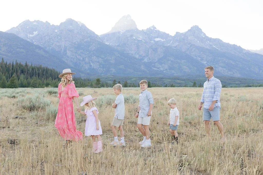 Family walking together through an open field with mountain views at Jenny Lake Grand Teton