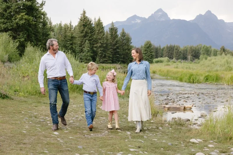 Family at the Grand Tetons with kids taking a family portrait next the river.