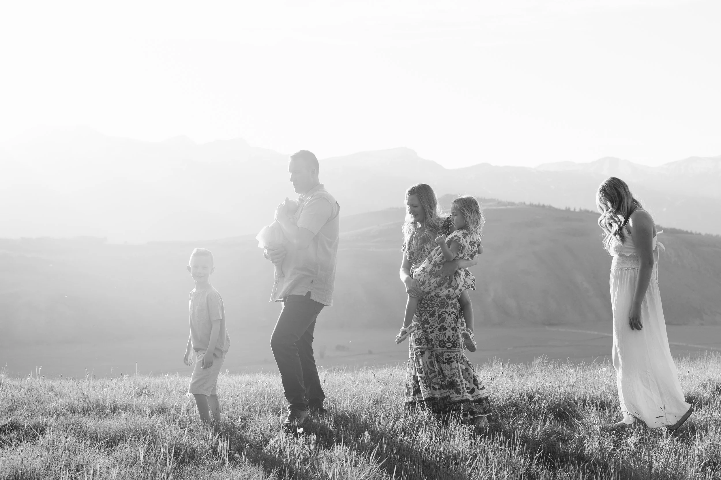 black and white photo of a family walking on a hill with mountains in the background