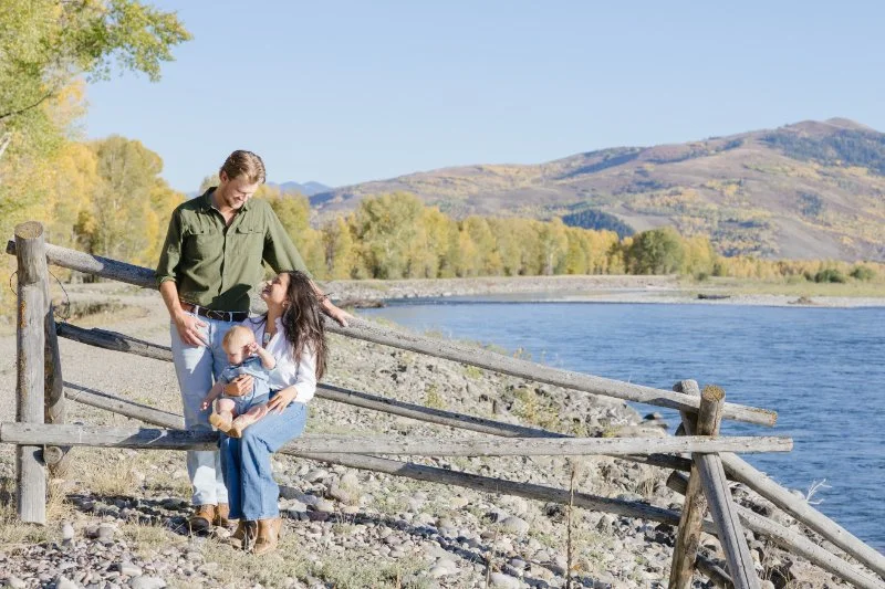 Family sitting by river with mountain views during a Grand Teton family photography session