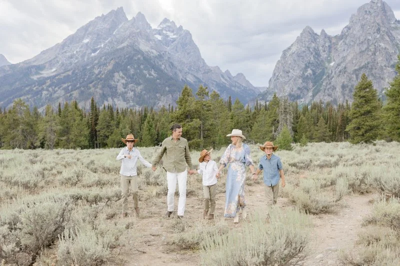 Family walking together through Grand Teton wildflowers with mountain views in the background