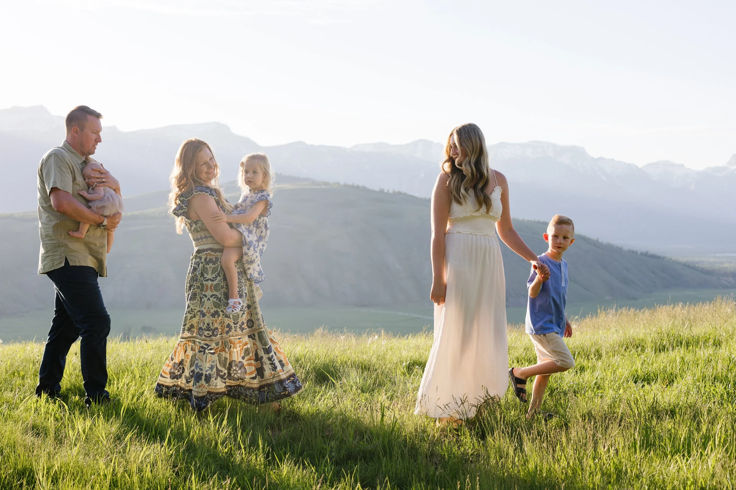 a sunny photo of a family of 5 walking in the grass during their summer family photos