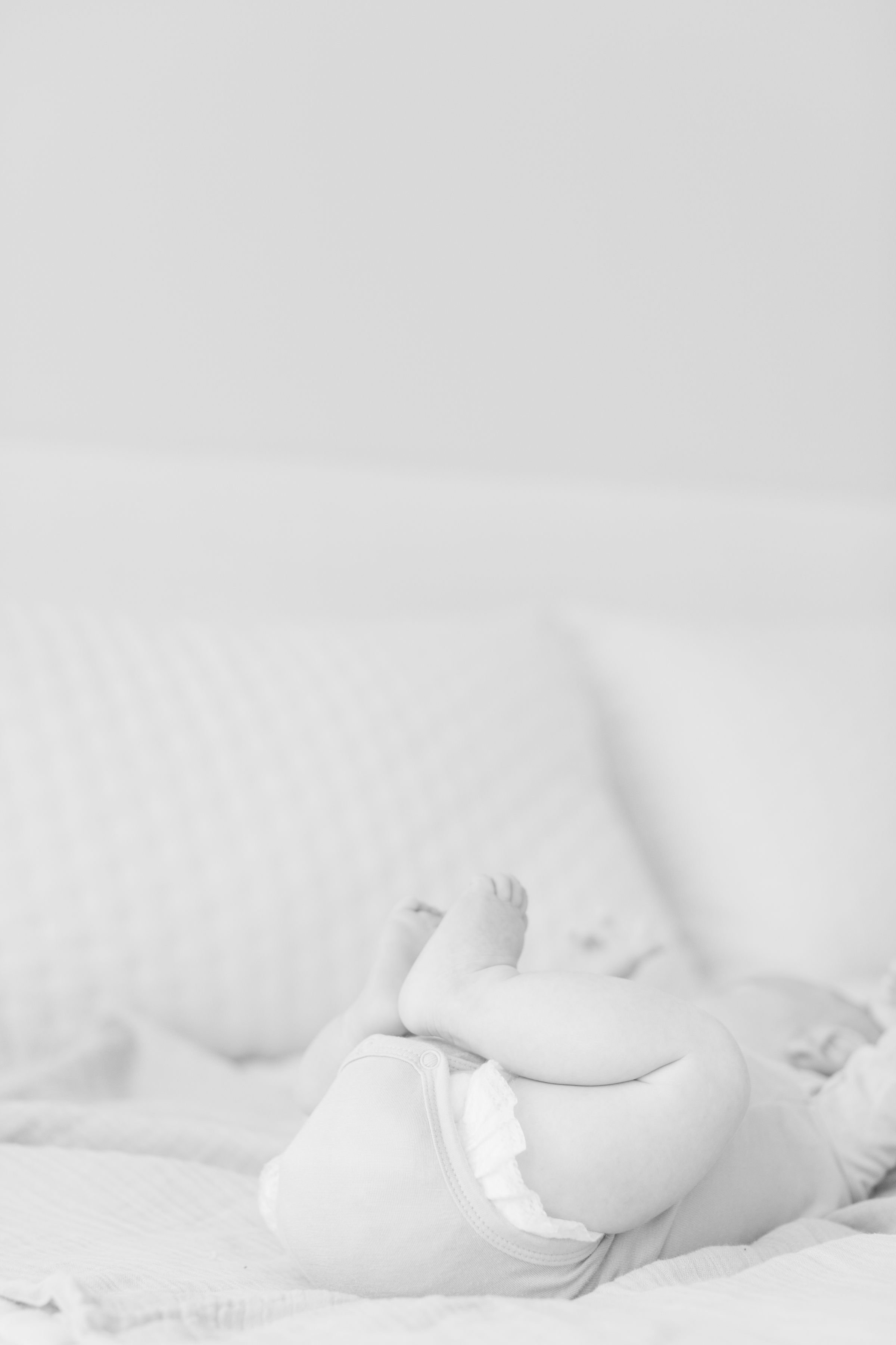 black and white photo of a young baby on a bed with his feet in the air- Jackson Hole family photographer