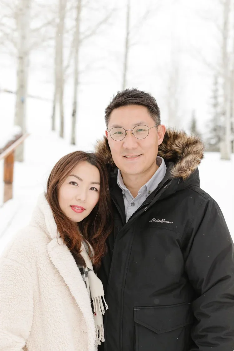 Couple poses for photo, surrounded by falling snow.