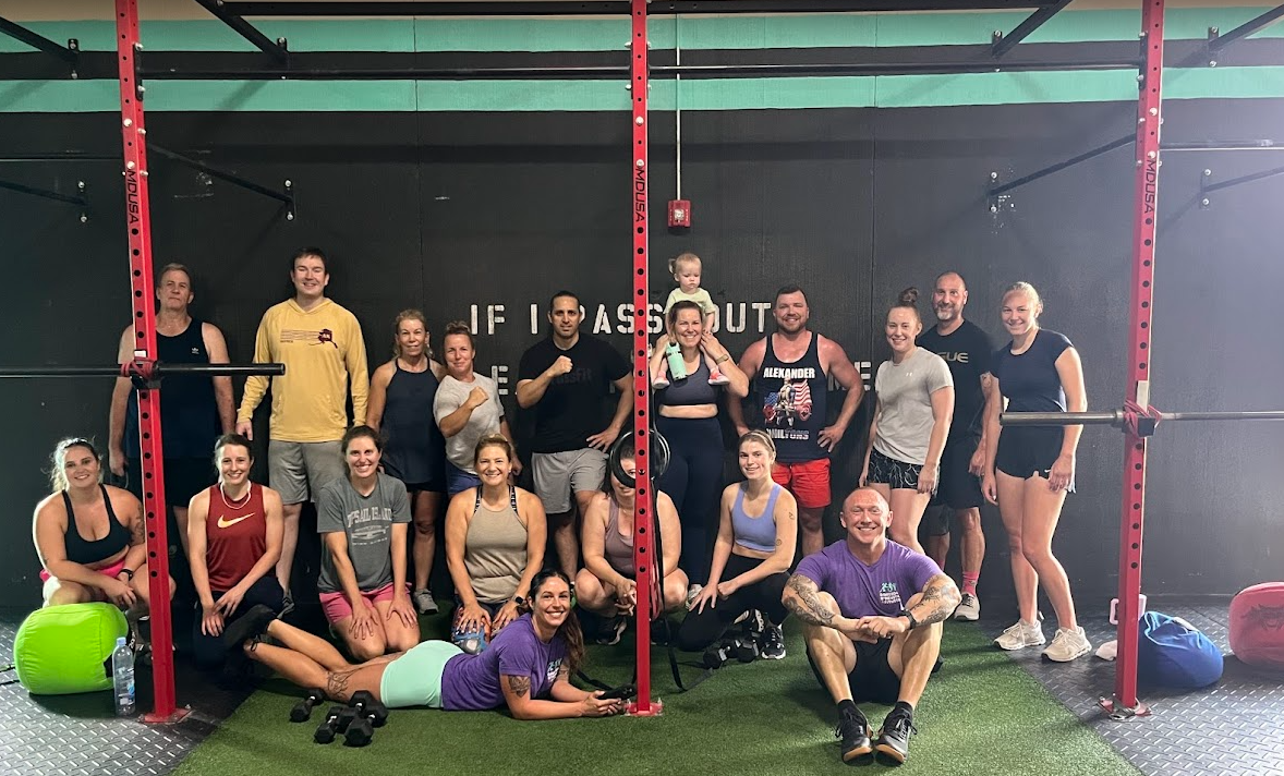 Group of people smiling for the camera. One row standing, one row kneeling and two people on the floor.
