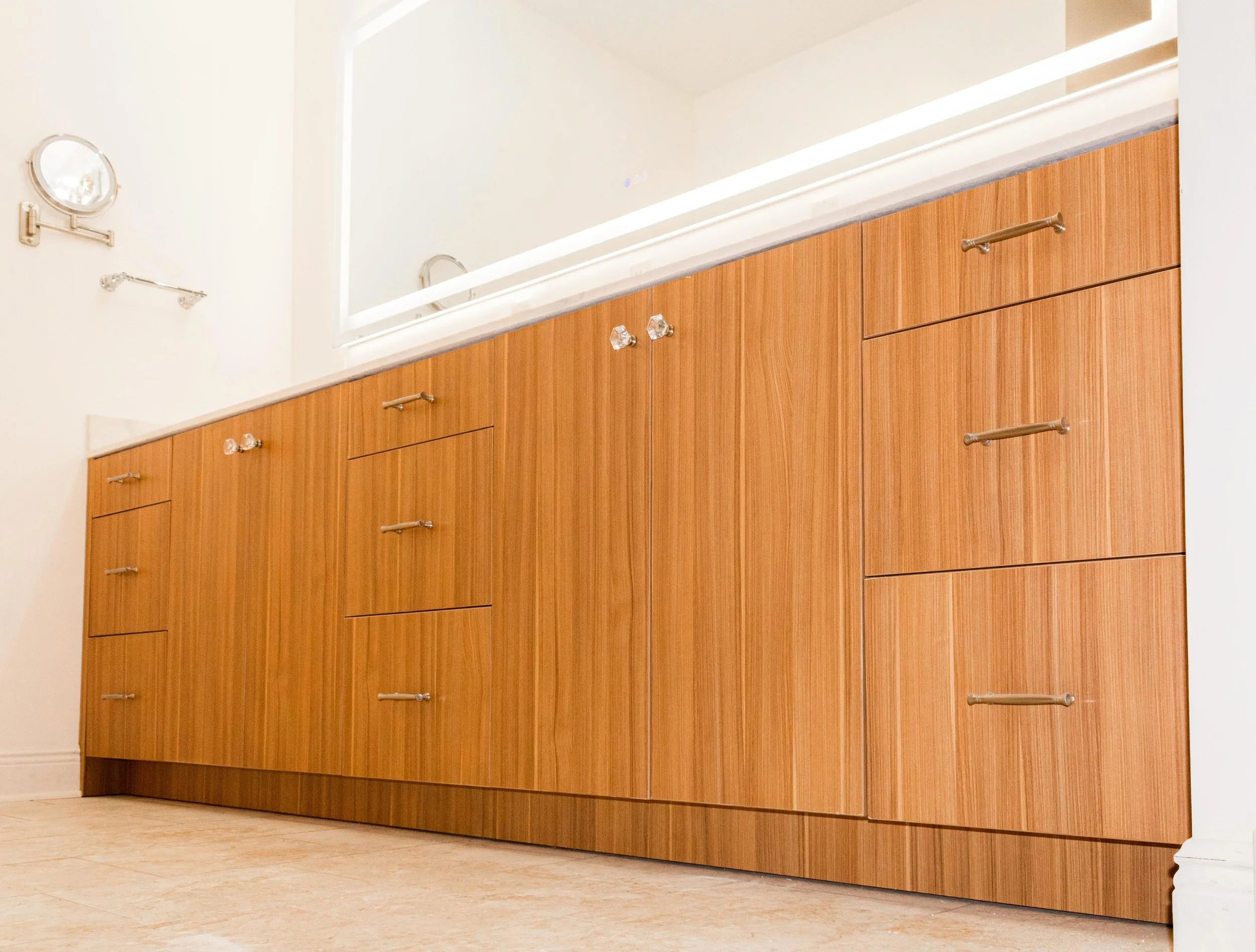 A wooden cabinet with multiple drawers and silver handles in a room with light-colored walls and light flooring.