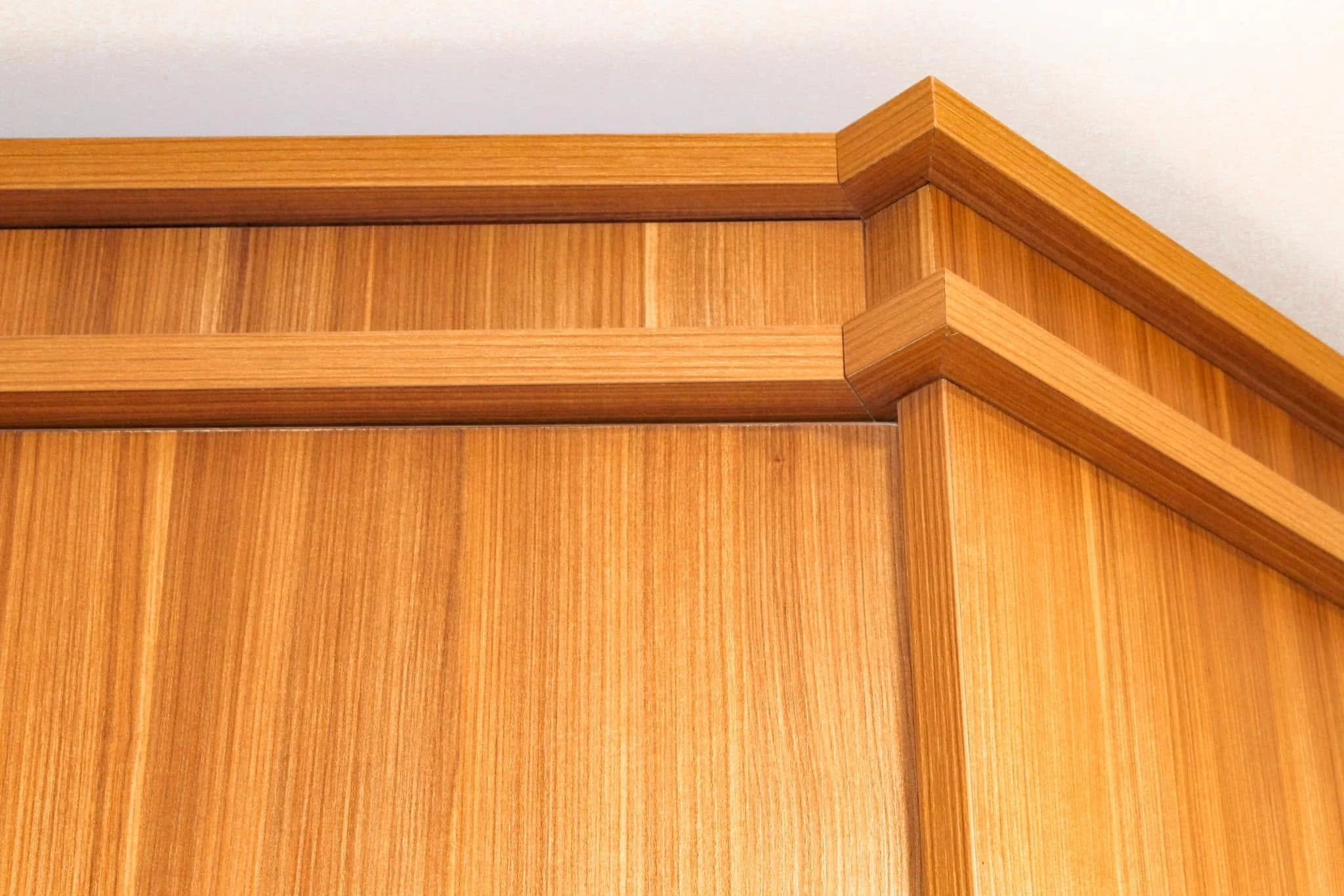 Close-up view of wooden corner molding and wall paneling in natural wood finish.