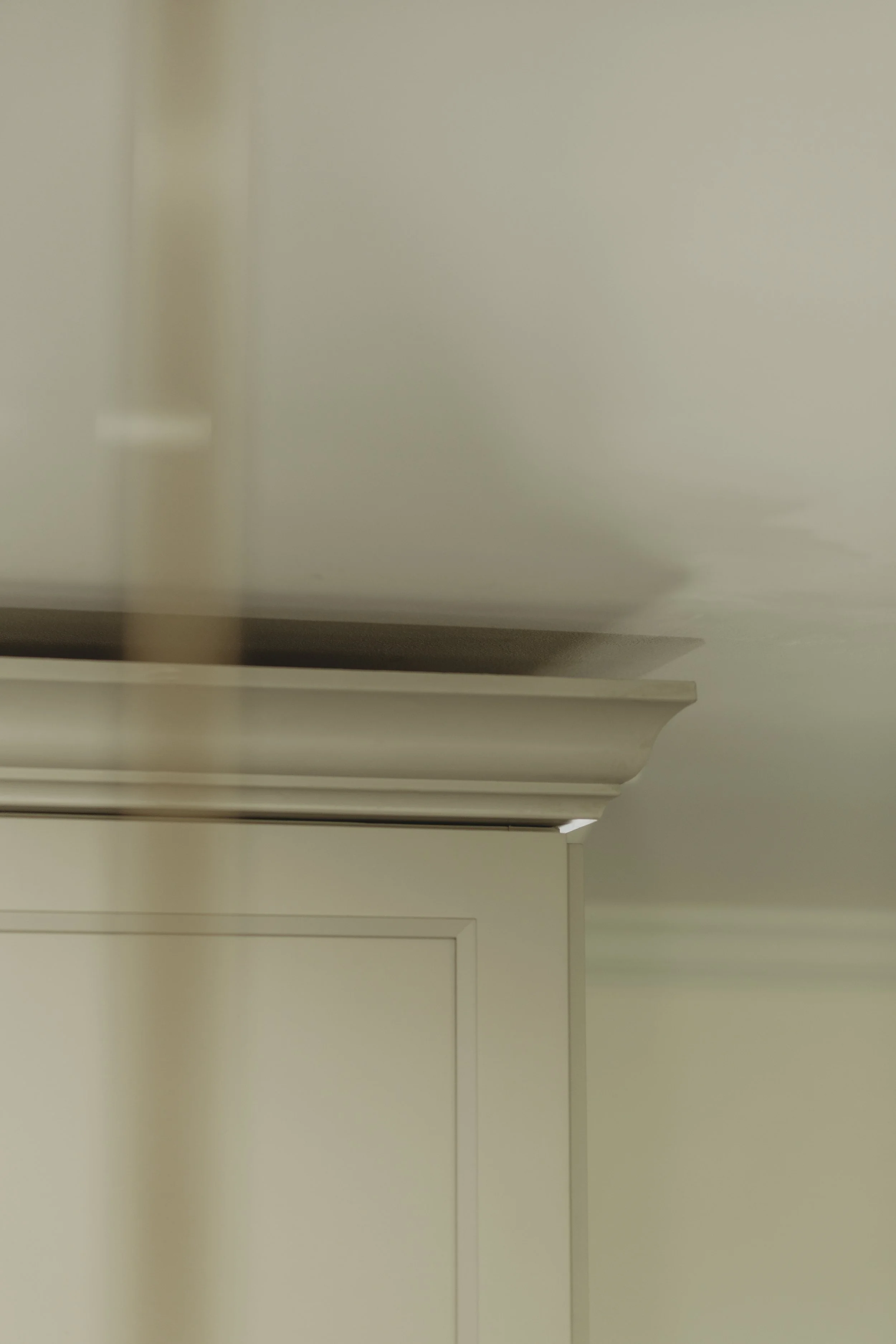 Close-up view of a kitchen range hood installed above a kitchen stove, with beige walls and cabinetry visible.