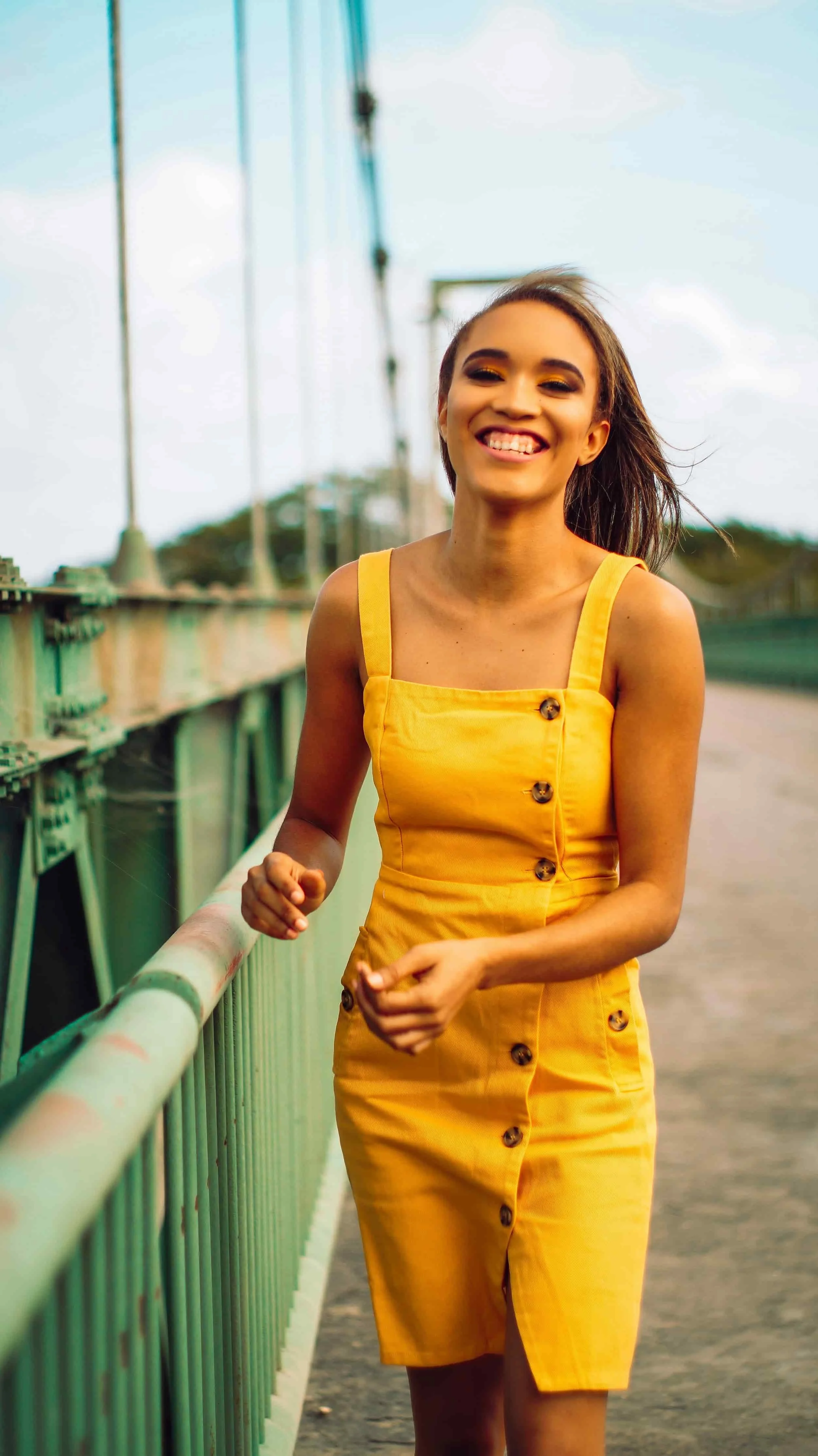 Woman of color smiling and walking confidently on a bridge, representing healing, self-trust, and releasing guilt through therapy.