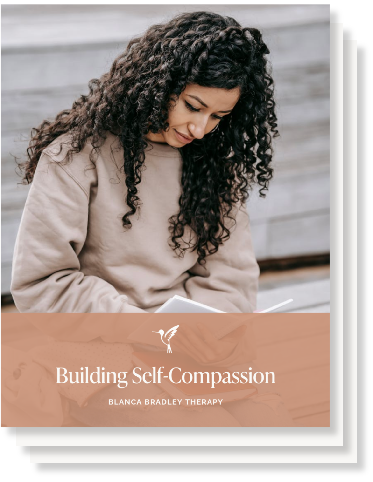 A woman with curly dark hair, wearing a beige sweatshirt, looking down and smiling, against a gray wooden background.