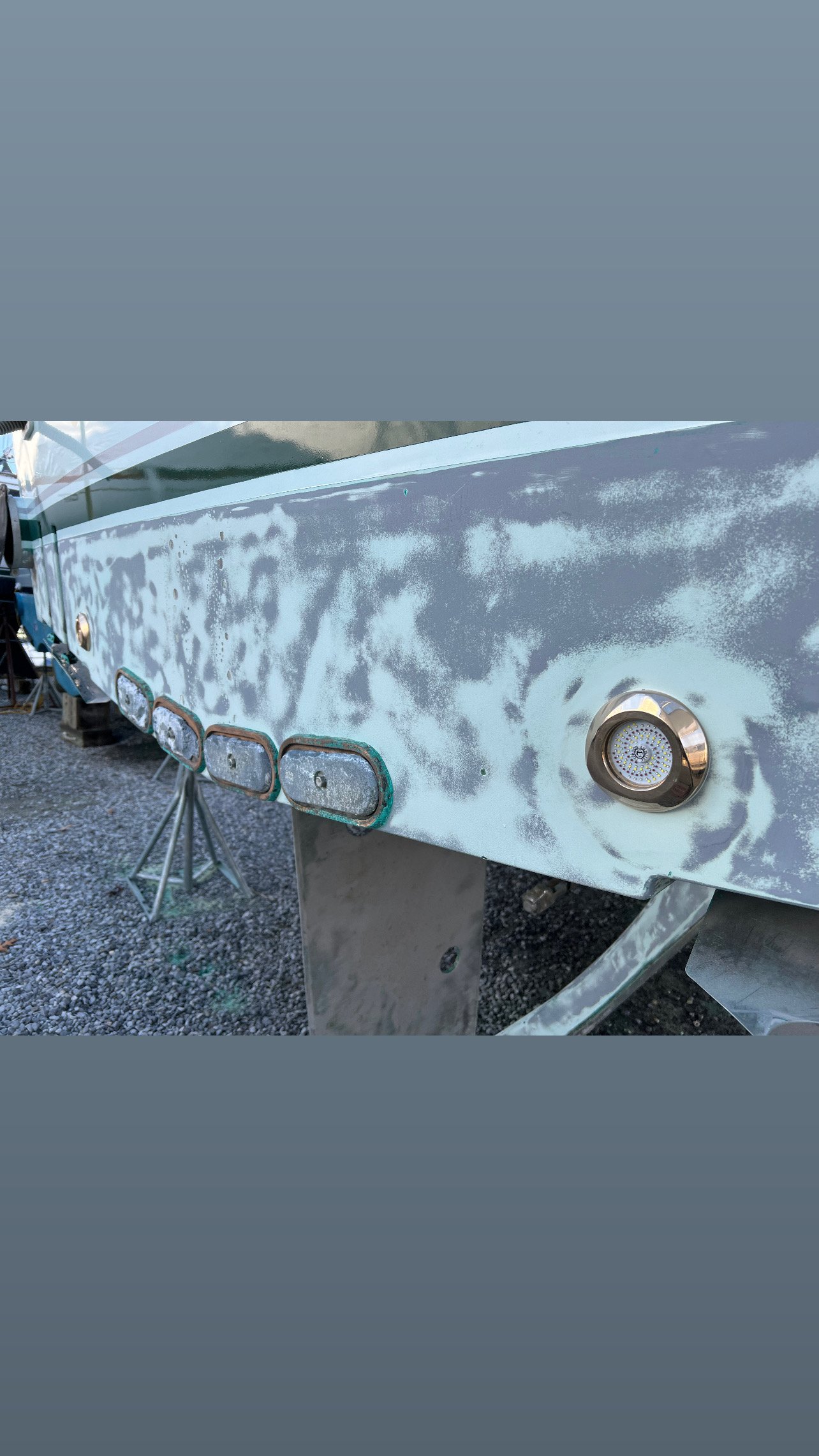 westmac Close-up of a boat hull with several weathered port window frames and a LED underwater light.