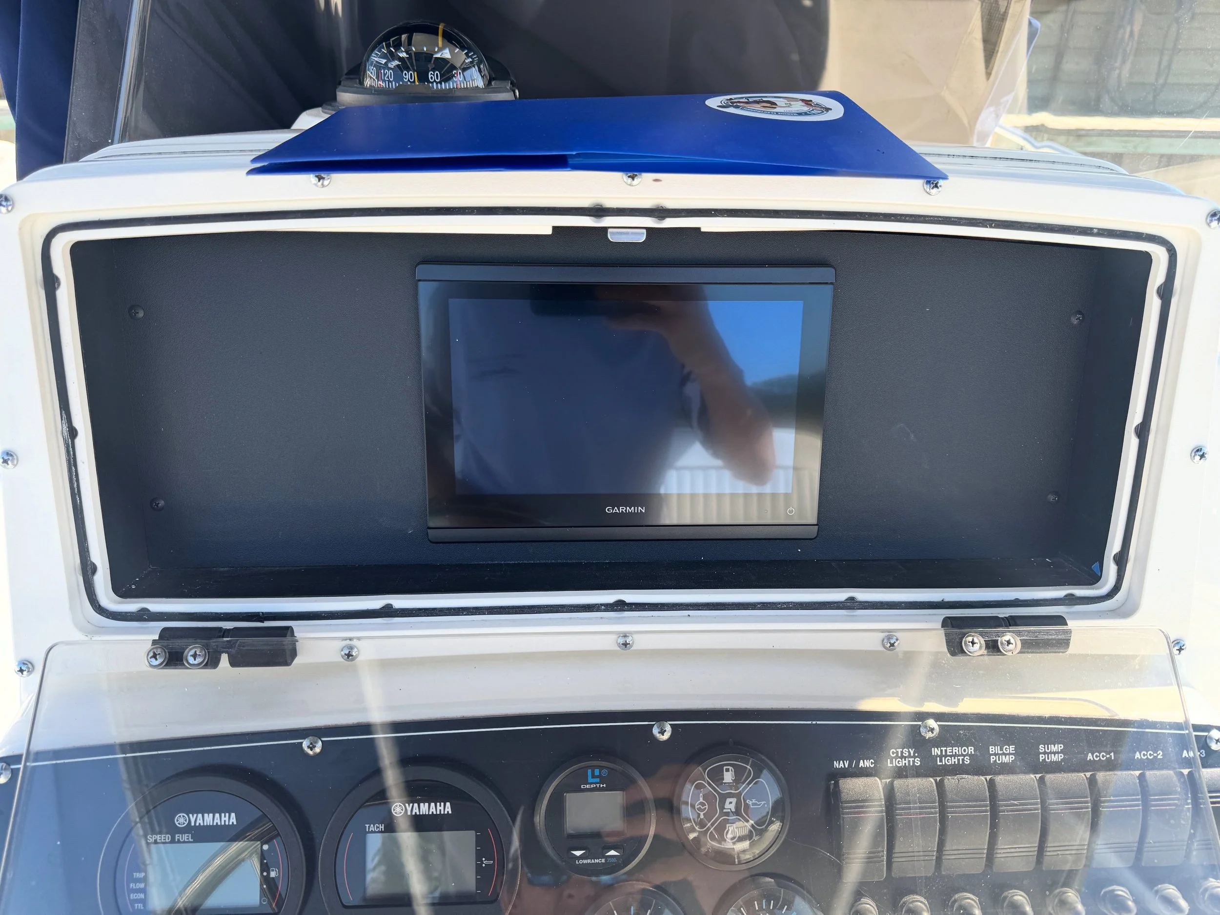 Instrument panel of a boat or vehicle, featuring a Garmin screen, Yamaha speed and fuel gauges, and various switches and indicators.