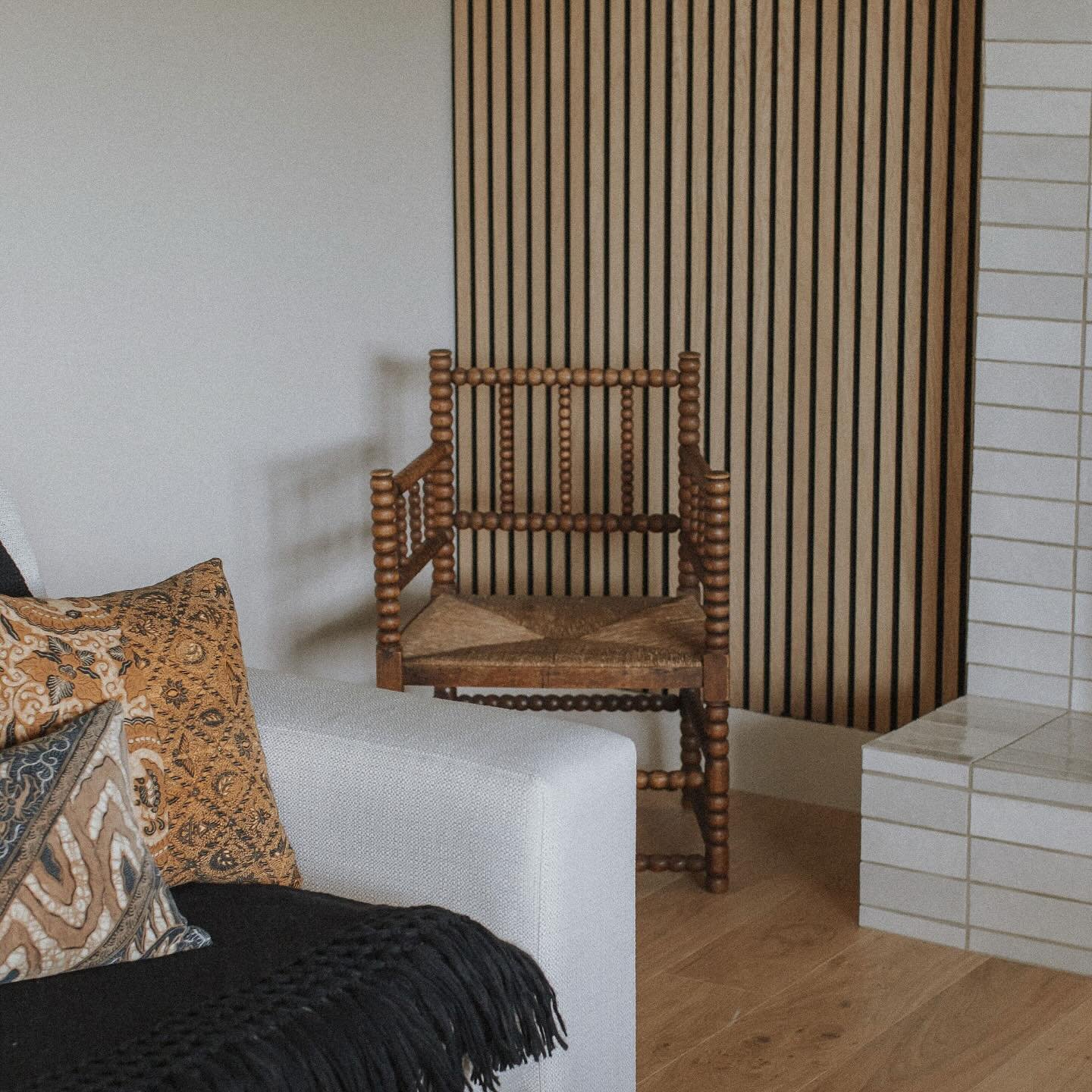A quiet moment where texture does the talking. The warmth of slatted wood paneling plays against the cool touch of handmade tile, while layered textiles soften the architecture with pattern and patina. A vintage bobbin chair adds soul and history, si