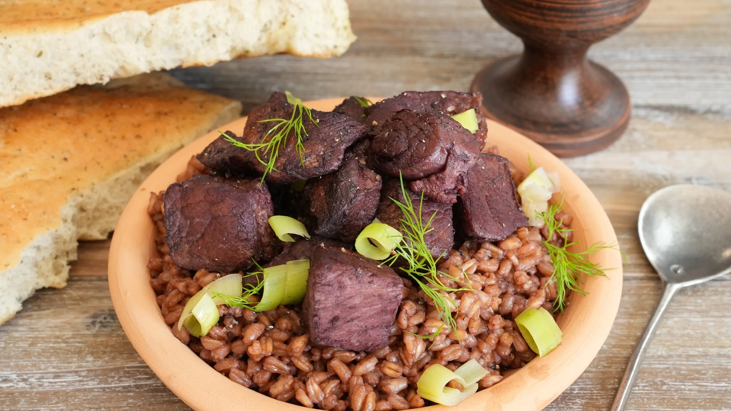 farro cooked in wine sauce topped with bite size pieces of simmered pork with chopped leek and fresh dill