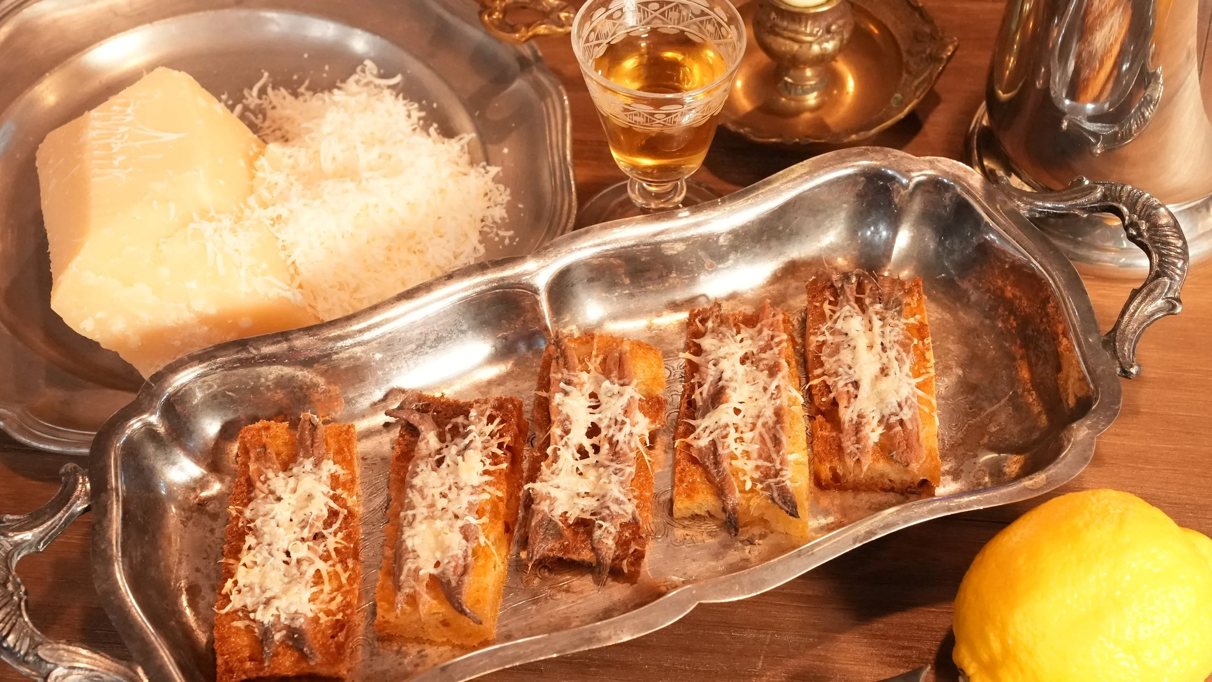 rectangle toast topped with anchovy filets and melted grated parmesan