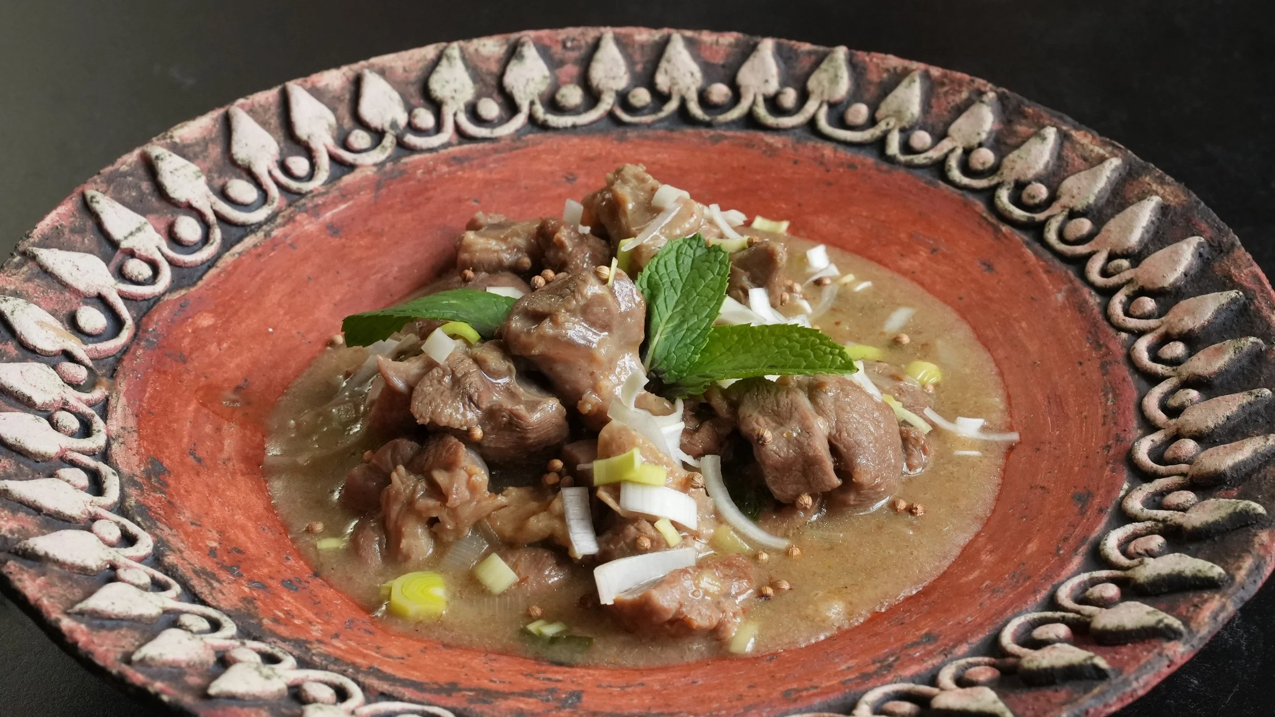 lamb stew garnished with fresh leeks fresh mint coriander seeds