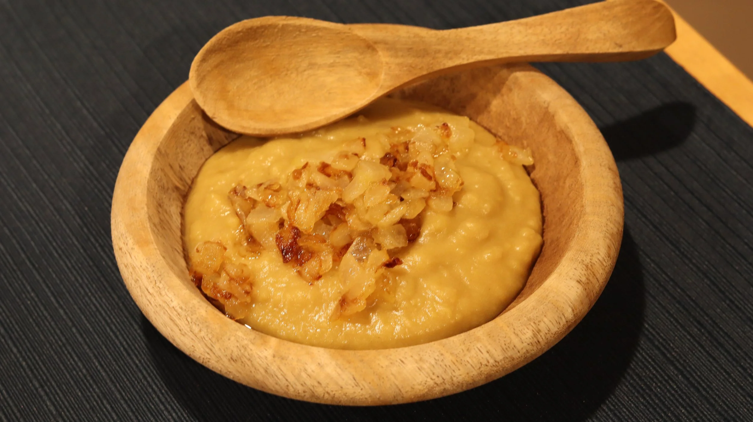 mashed bean porridge with fried onions in wooden bowl