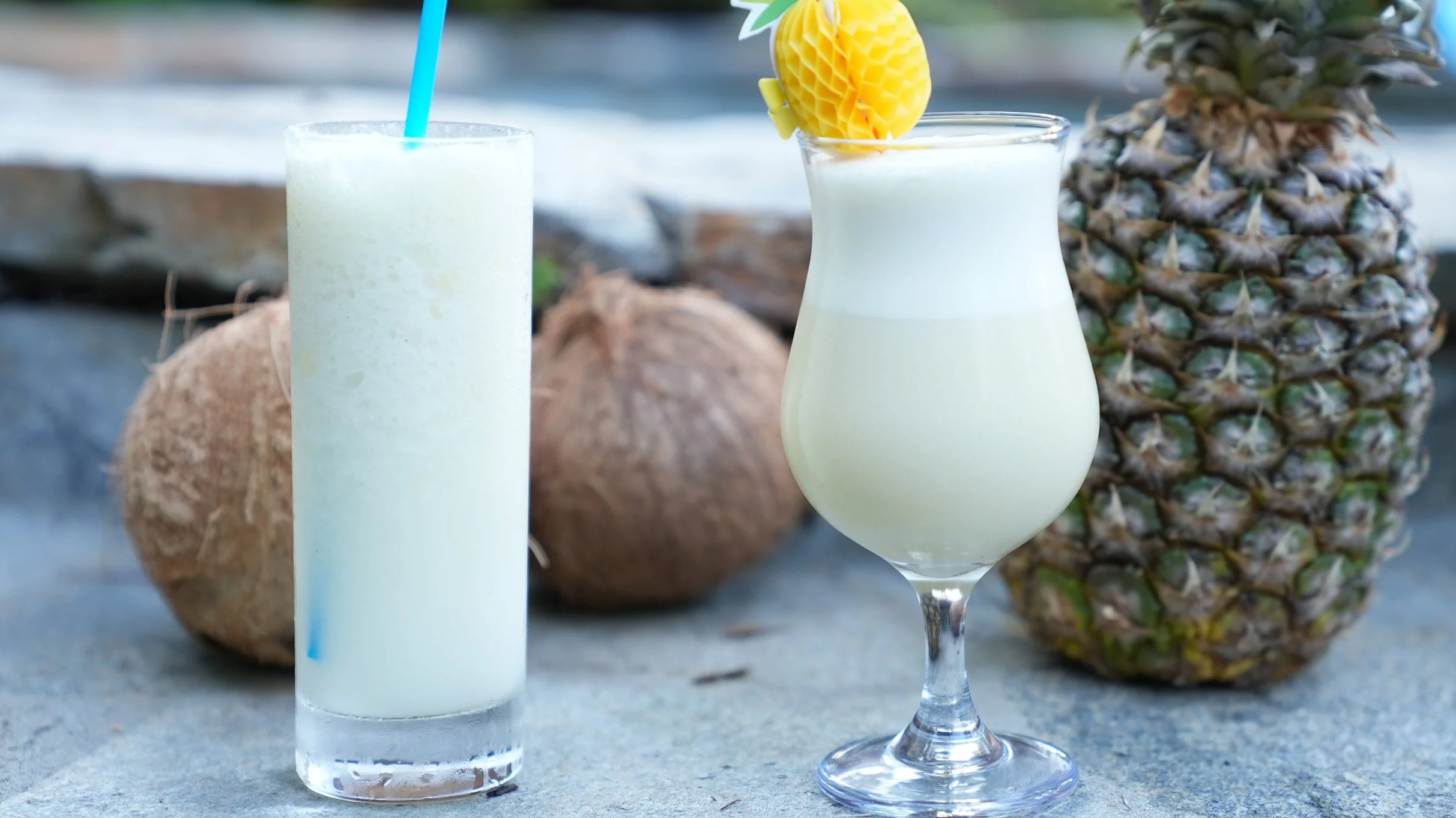 less creamy old style piña colada in a collins glass with straw, creamy modern version piña colada in a hurricane glass with straw