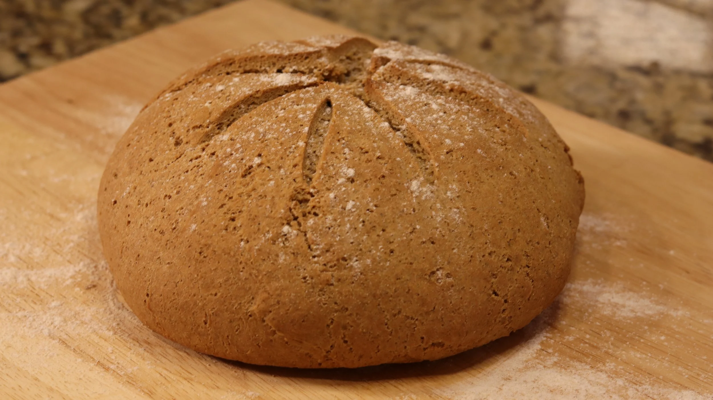 round loaf of coarse brown bread with star shape scored on top