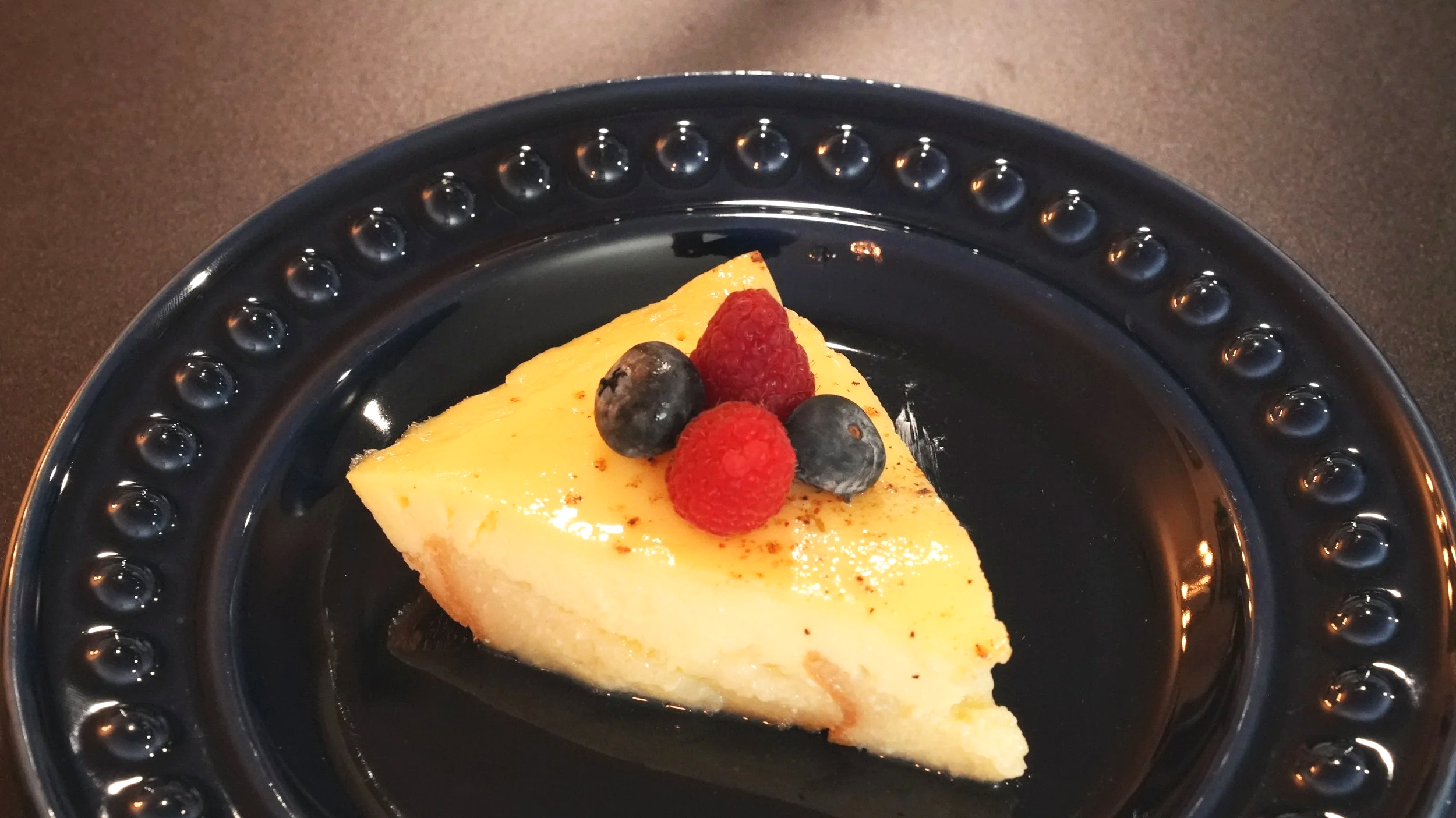 slice of egg custard in a crust of buttered bread with nutmeg and assorted berries on top