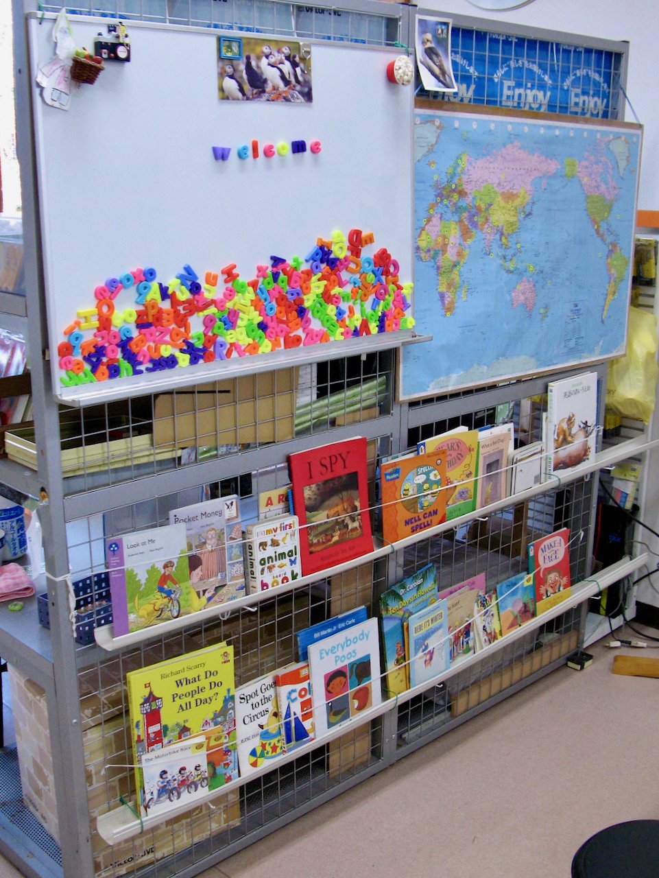 Book display , white board, colorful magnetic letters spelling out 'welcome' and a World map.