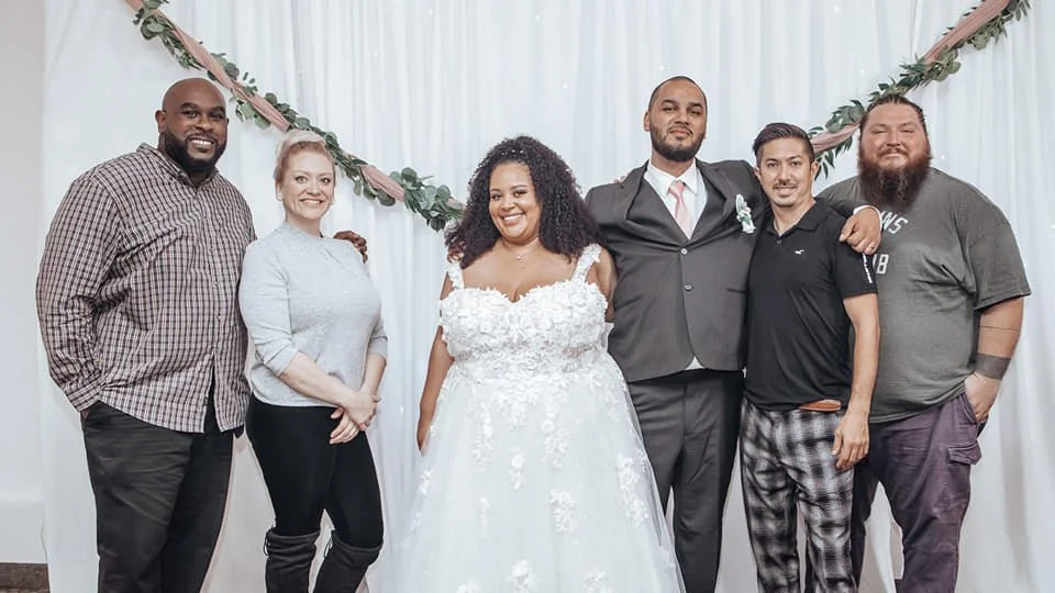 Members of the BlackTie Brothers team posing with a bride and groom at the end of their wedding day