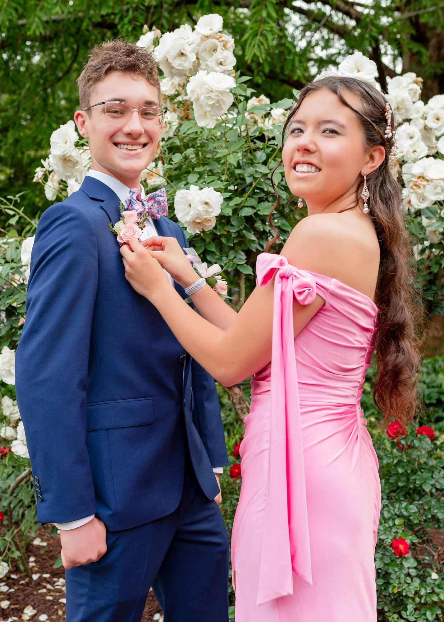 A female high school student helps her date during a prom portrait session in Raleigh, NC.  The portrait session was shot by PixByDez Photography.