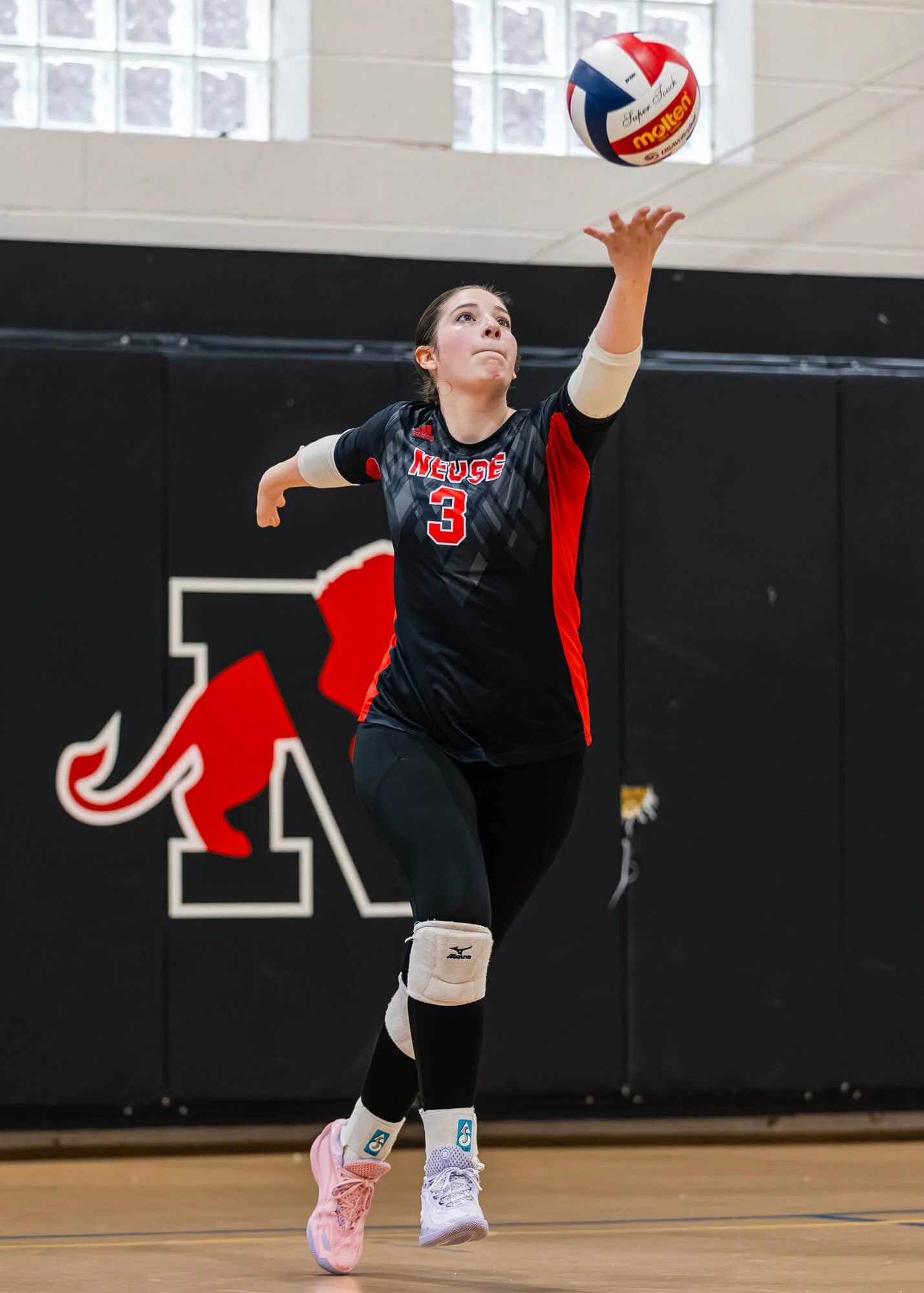 A Neuse Christian Academy varsity volleyball players serves the ball during a game in Raleigh, NC.  The photo was taken by PixByDez Photography a sports photographer based in Raleigh. 