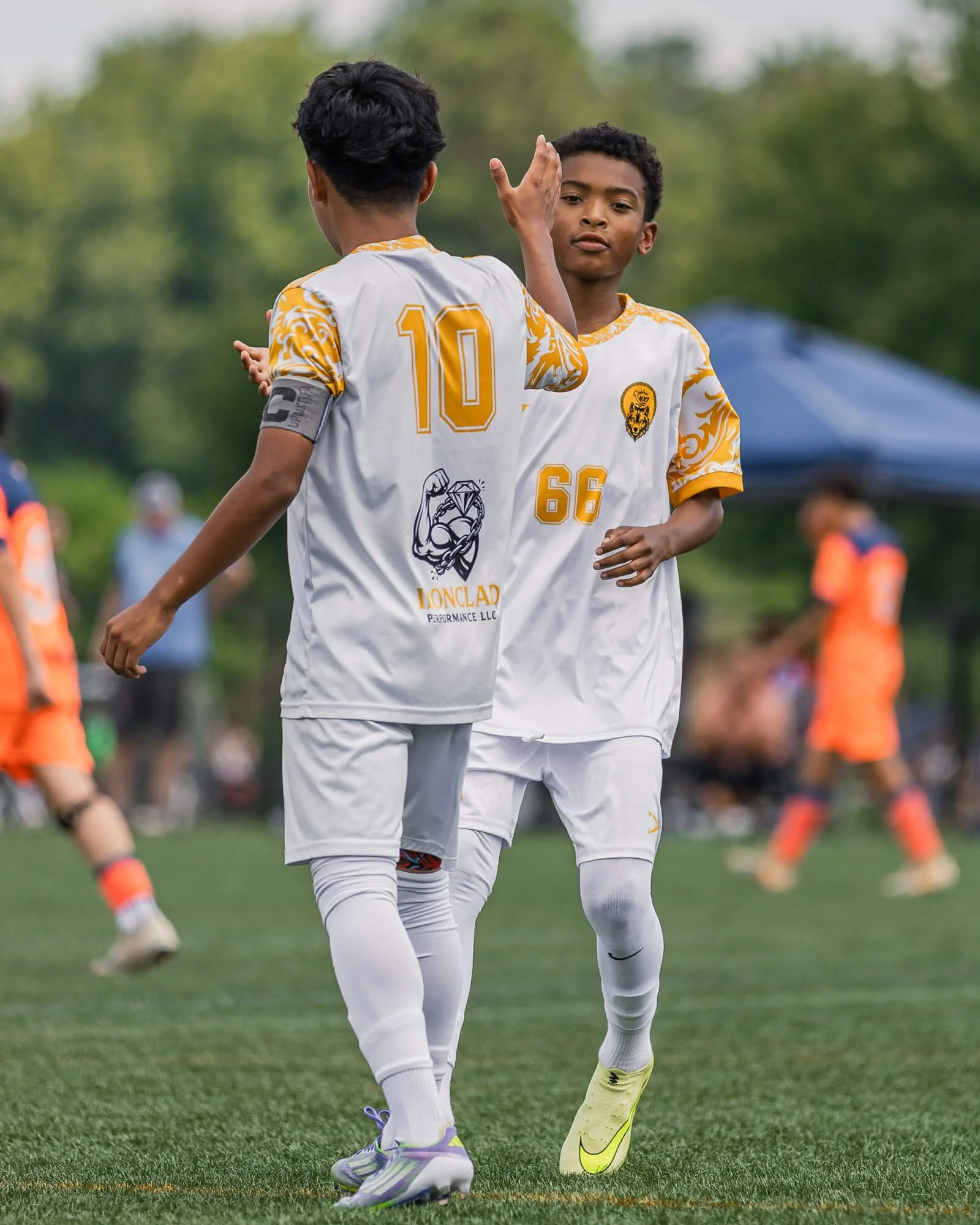 Two youth boys soccer players high five each other after a successful game in Raleigh, NC.  The photograph was taken by PixByDez Photography, a sports photographer based in Raleigh, NC