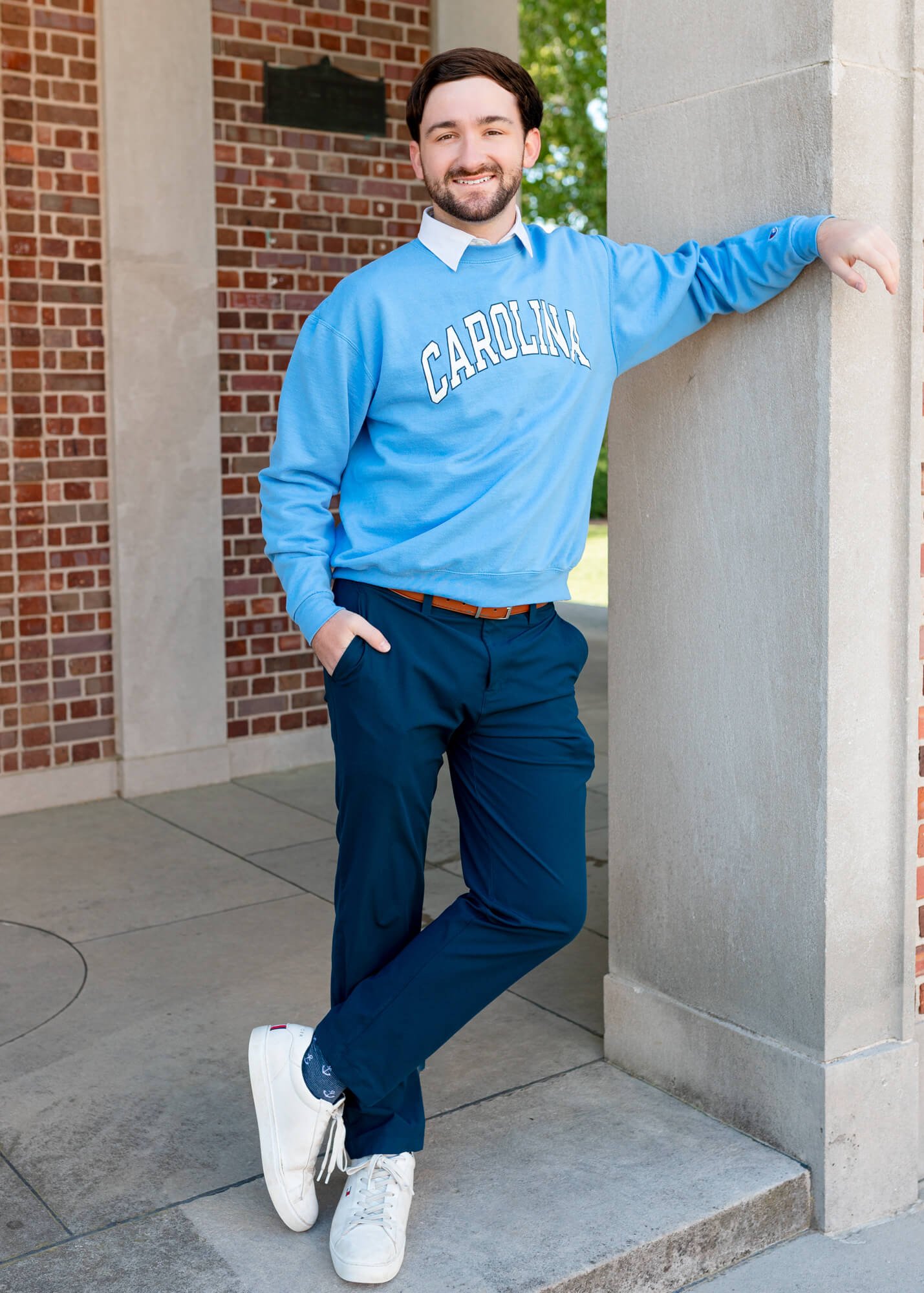 A male student student at UNC-CH (University of North Carolina at Chapel Hill) poses during a graduation portrait session at the Morehead-Patterson Bell Tower on campus in Chapel Hill, North Carolina