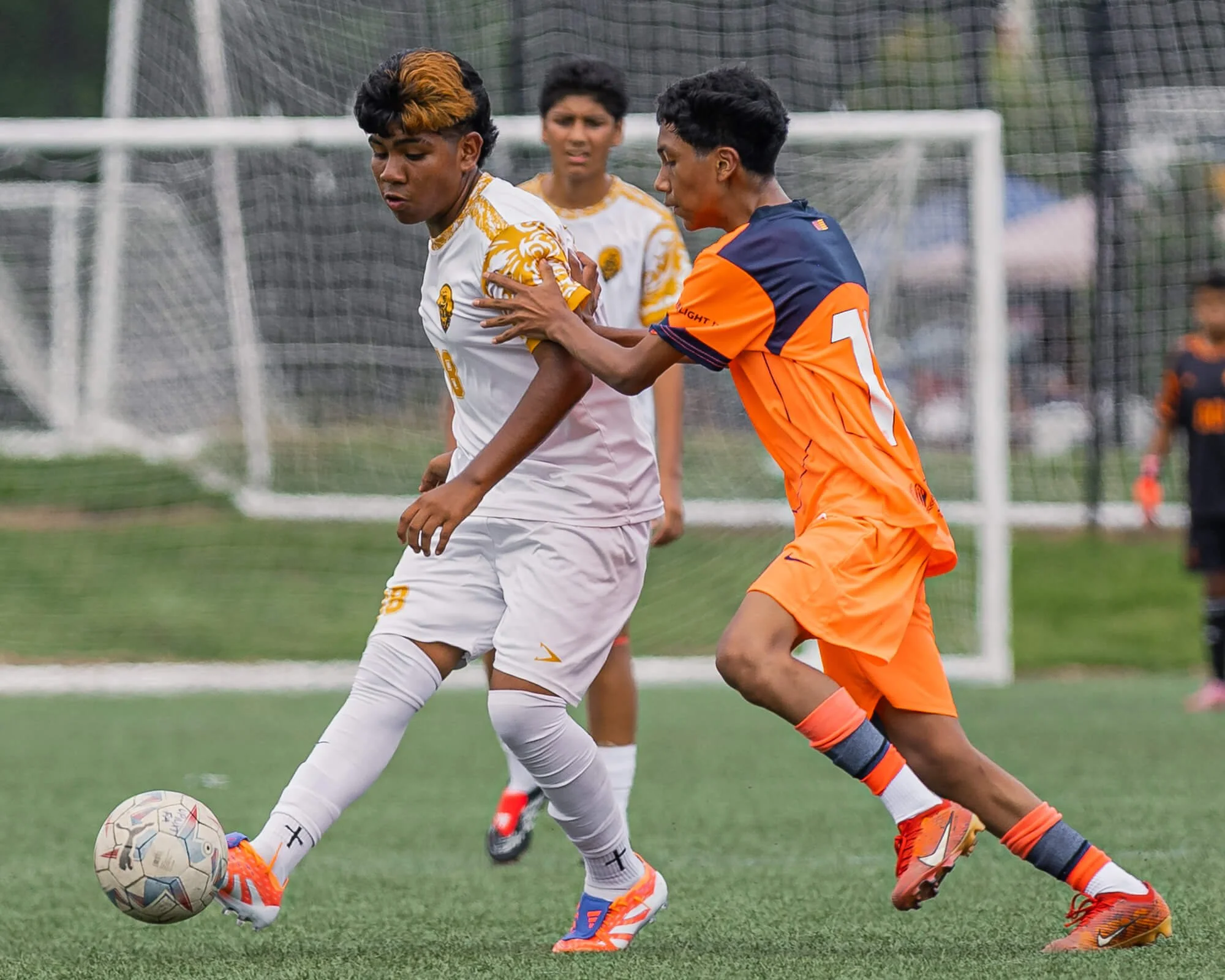 Two players fight for the ball during a youth soccer tournament game in Raleigh, NC.  The photograph was taken by PixByDez Photography, a sports photographer based in Raleigh, NC