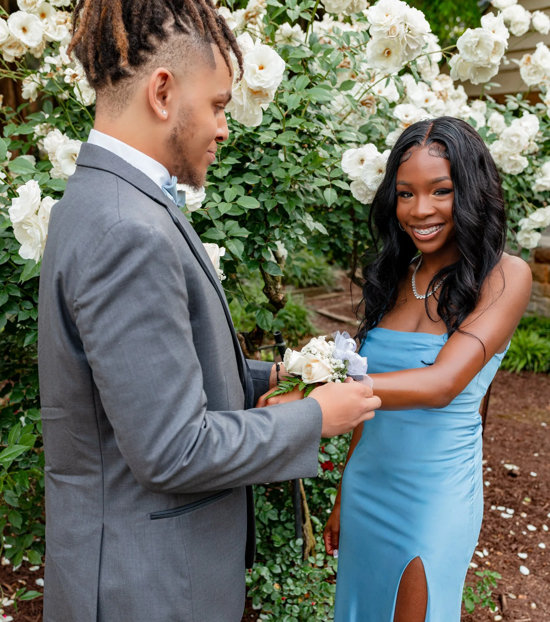 A high school student places a corsage on his date during a prom photo shoot at the Raleigh Rose Garden in Raleigh, NC