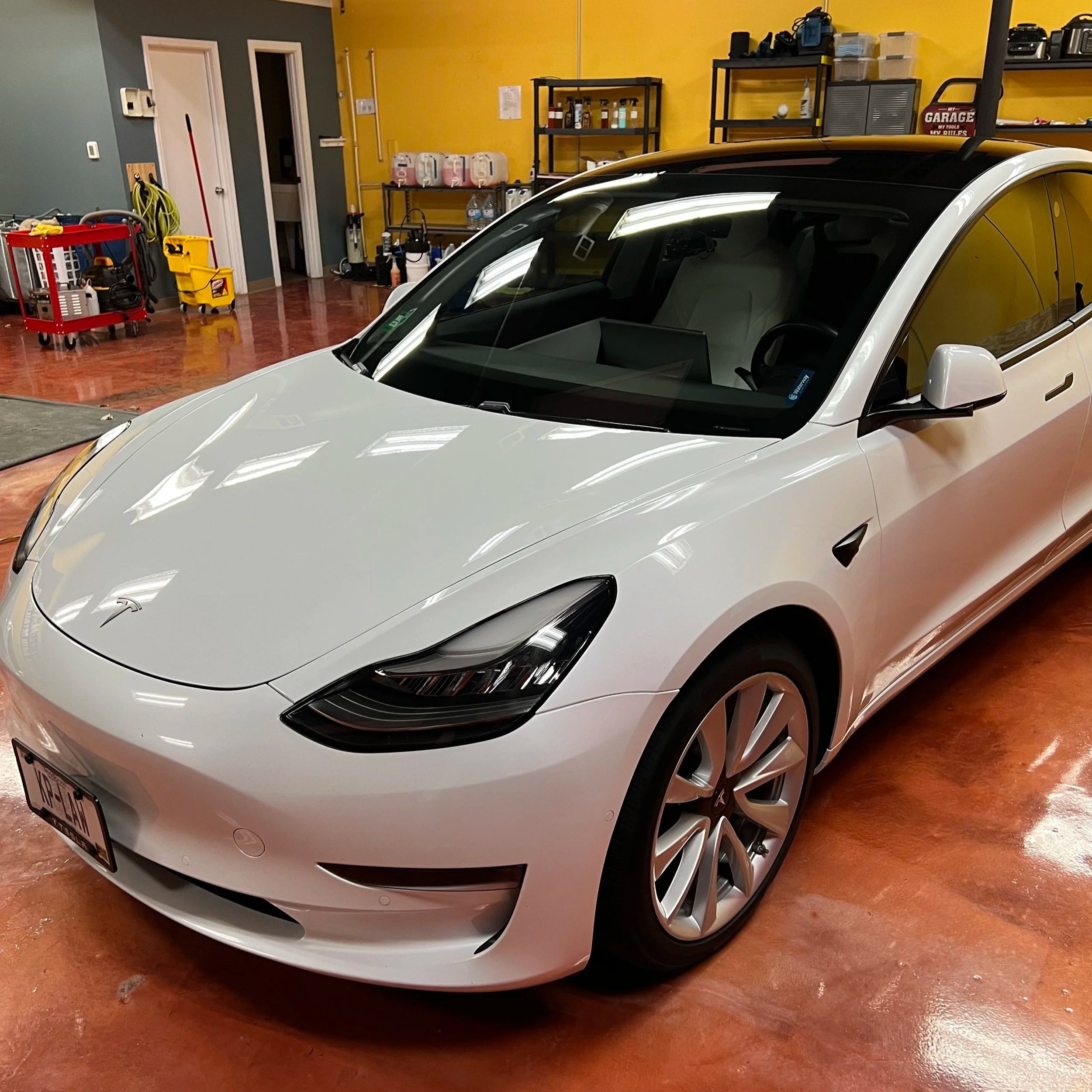 Technician installing professional window tint film on a car side window at Empire Customs Car Detailing in Kansas City.