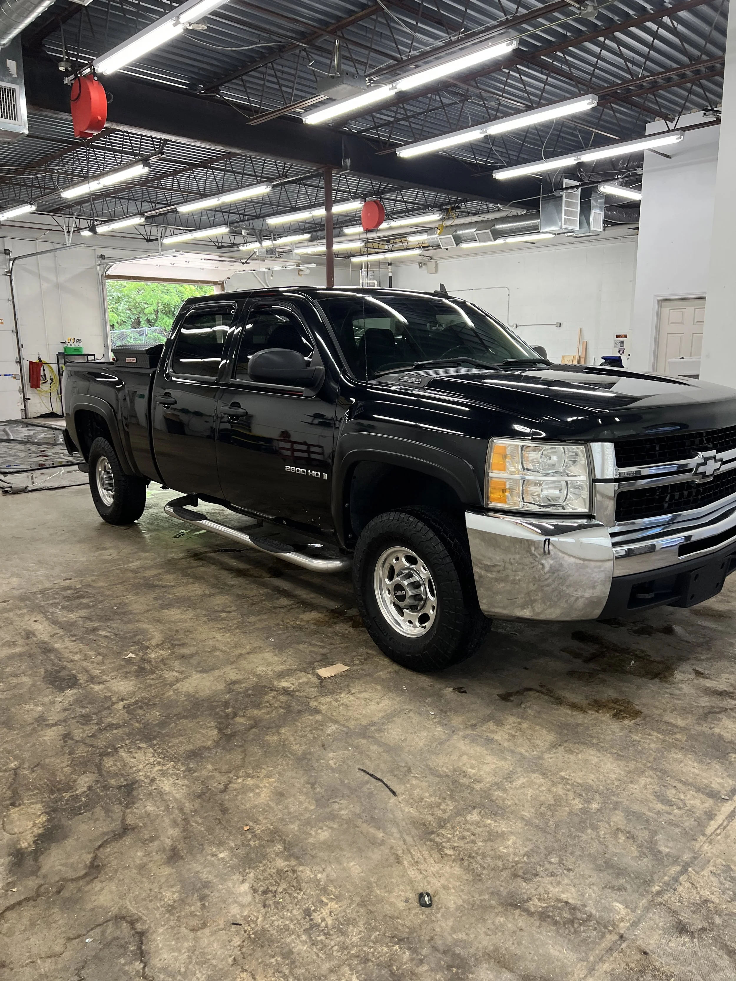 Technician installing professional window tint film on a car side window at Empire Customs Car Detailing in Kansas City.