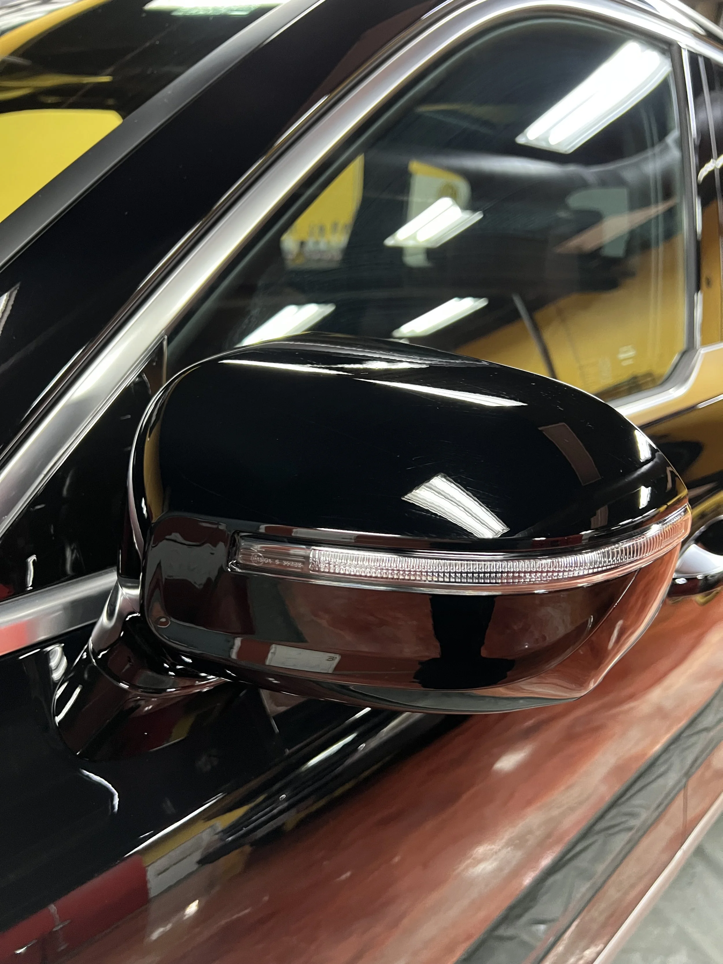 Detailer applying self healing paint protection film to a car side view mirror at Empire Customs Car Detailing in Kansas City.