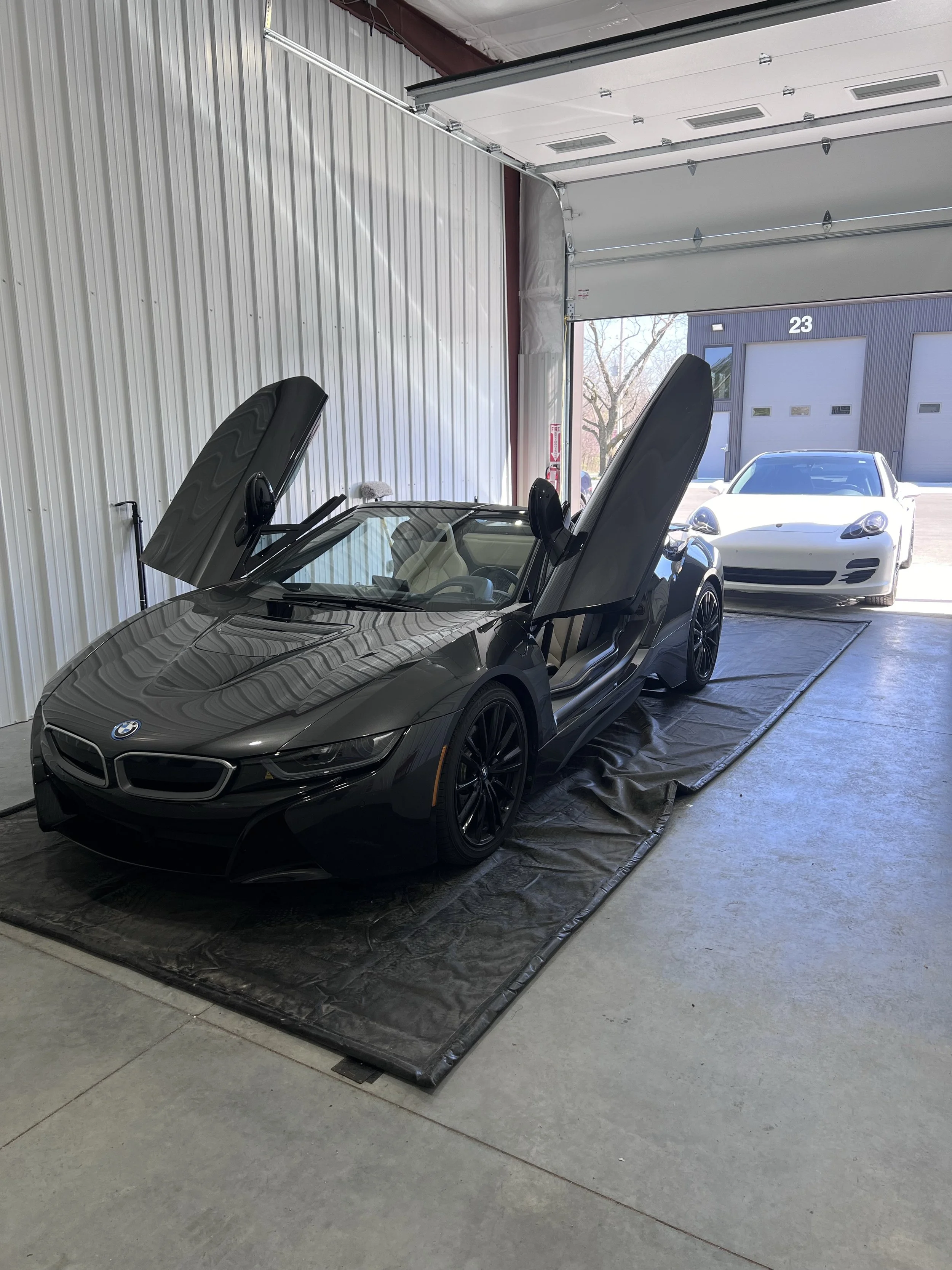 Detailer buffing wax off a car hood to reveal a deep reflective gloss.