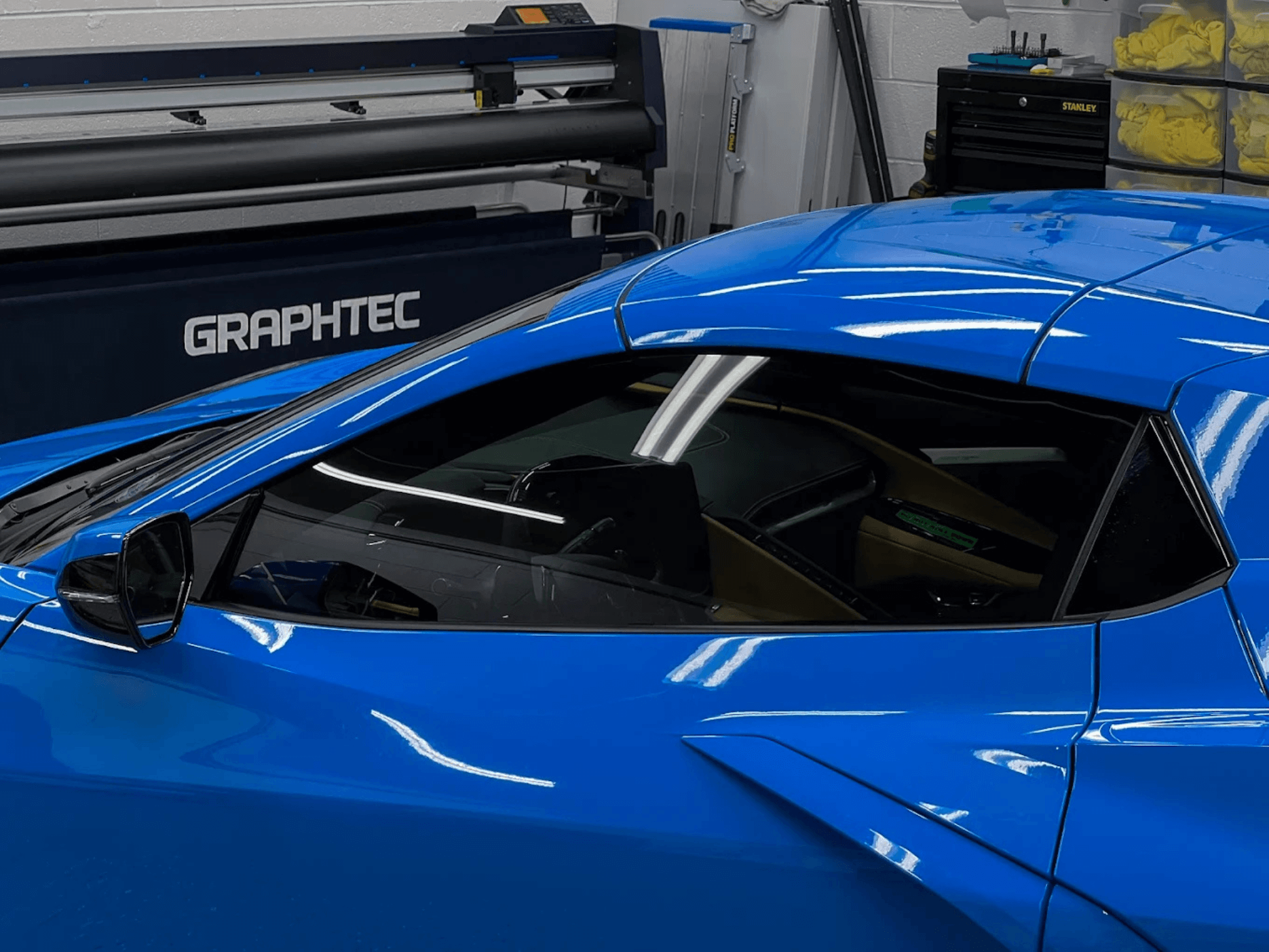 Technician installing high quality ceramic window tint on car windshield for reduced glare.