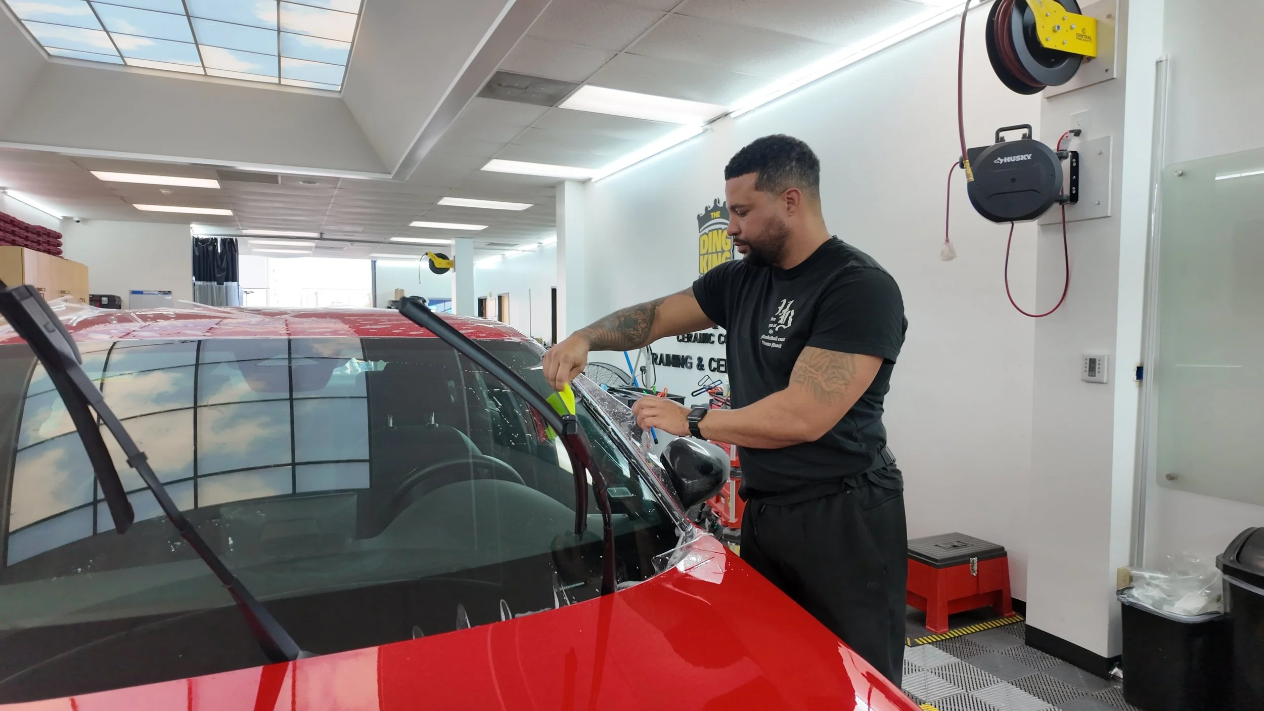 Technician carefully removing old paint protection film PPF from a vehicle at Empire Customs Car Detailing in Kansas City to restore paint and prepare for new film installation.