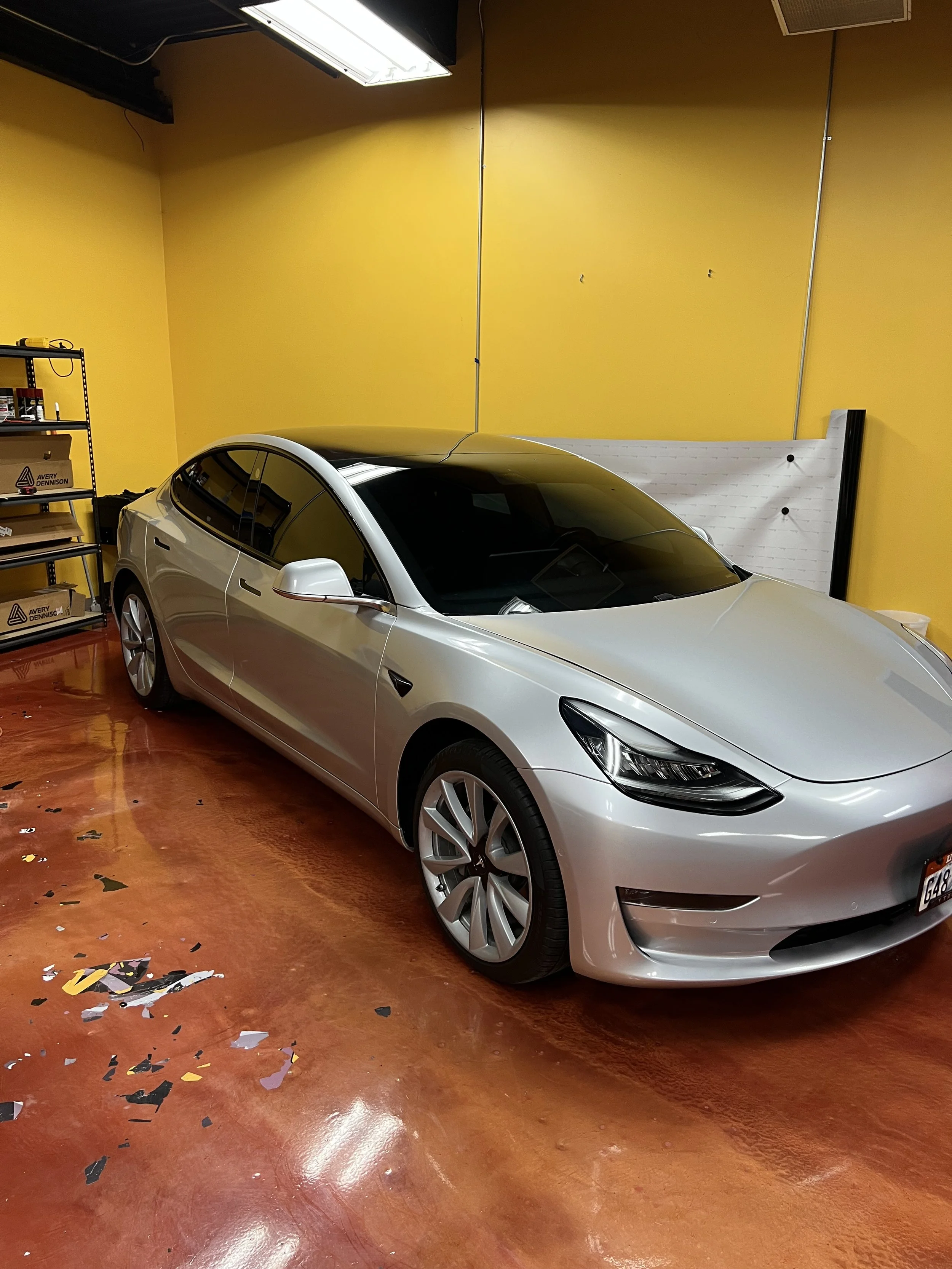 Car in the shop with tint film being applied to the windshield to improve heat rejection and reduce glare.